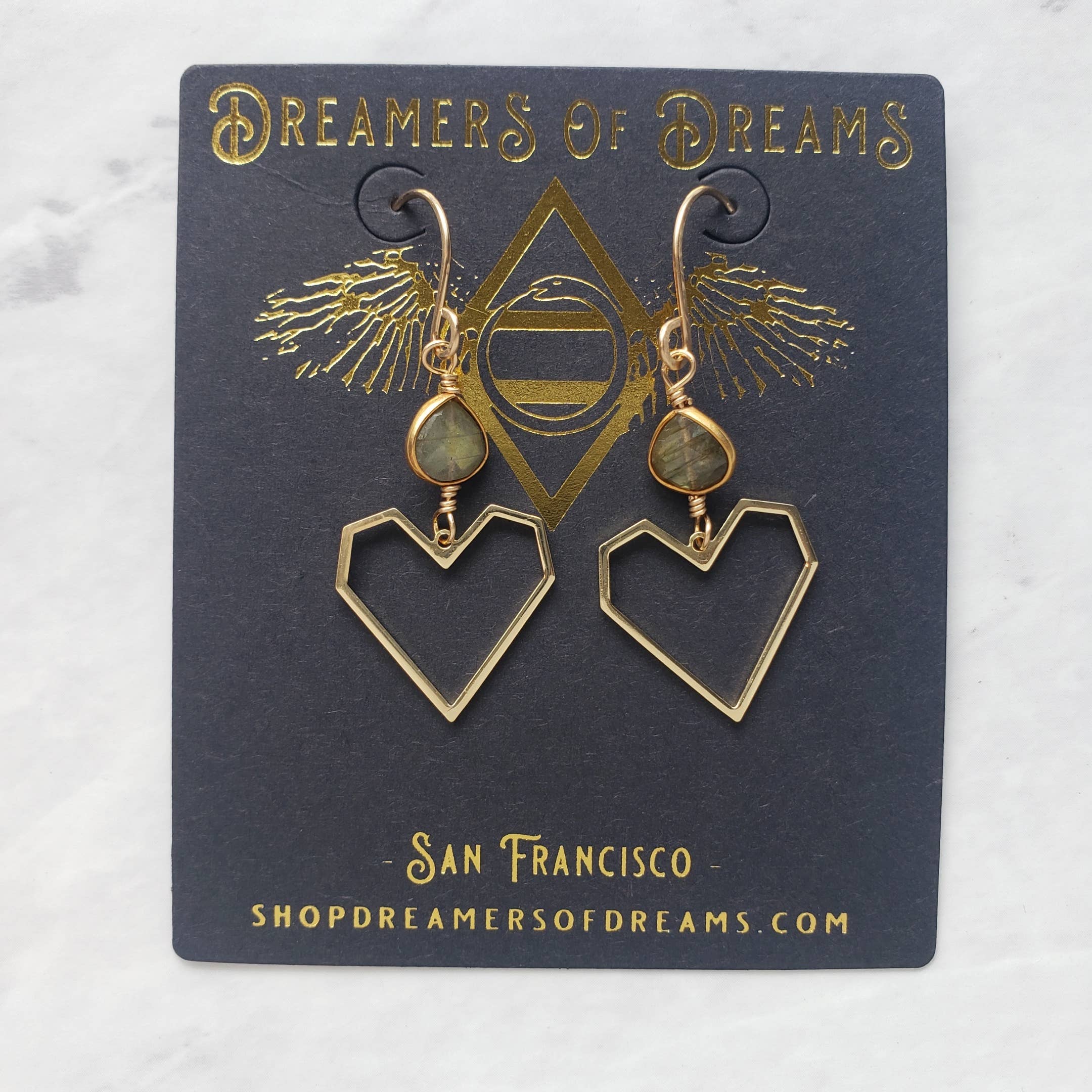 Elevate your look with Geometric Heart Labradorite Earrings by Dreamers of Dreams, featuring 14K gold fill, green labradorite stones, and a navy card with the brand’s gold logo—perfect for fans of unique jewelry.