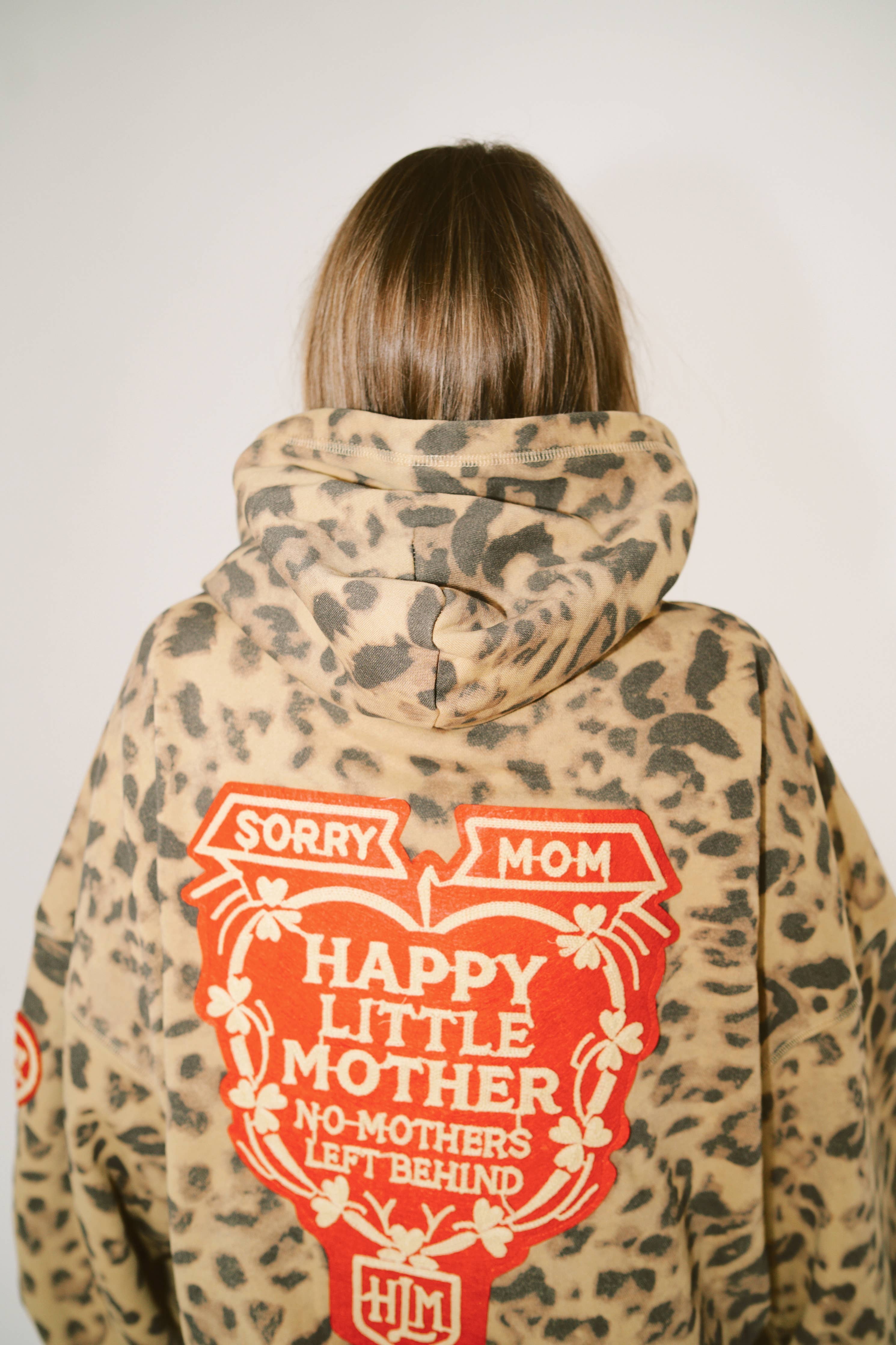 Person wearing leopard print hoodie with red heart graphic and text SORRY MOM HOODIE - PRESALE on back