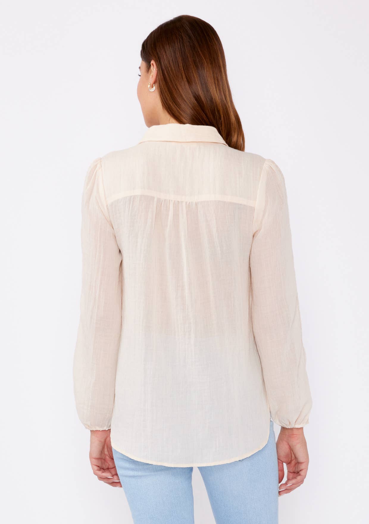 Back view of a woman wearing a beige Crinkled Lace Long Sleeve Button Down Blouse with light blue jeans.