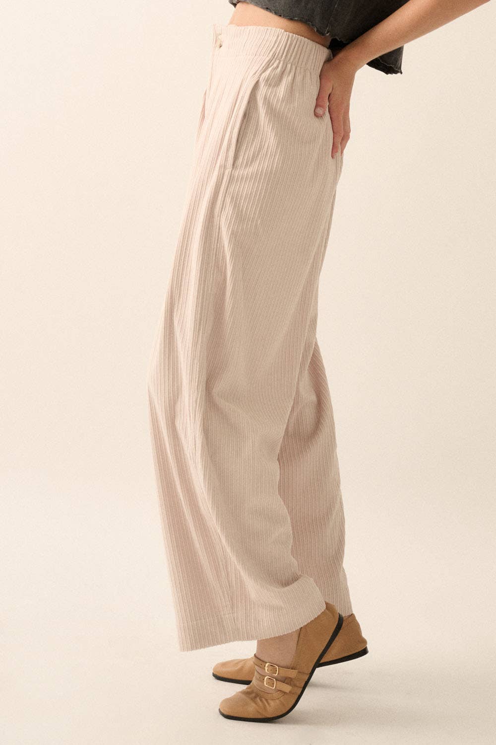 A person stands sideways wearing Promesa USA Velvet Corduroy Pleat-Front Wide-Leg Pants and tan buckled shoes. Only the lower torso and legs are shown against a plain, neutral background.