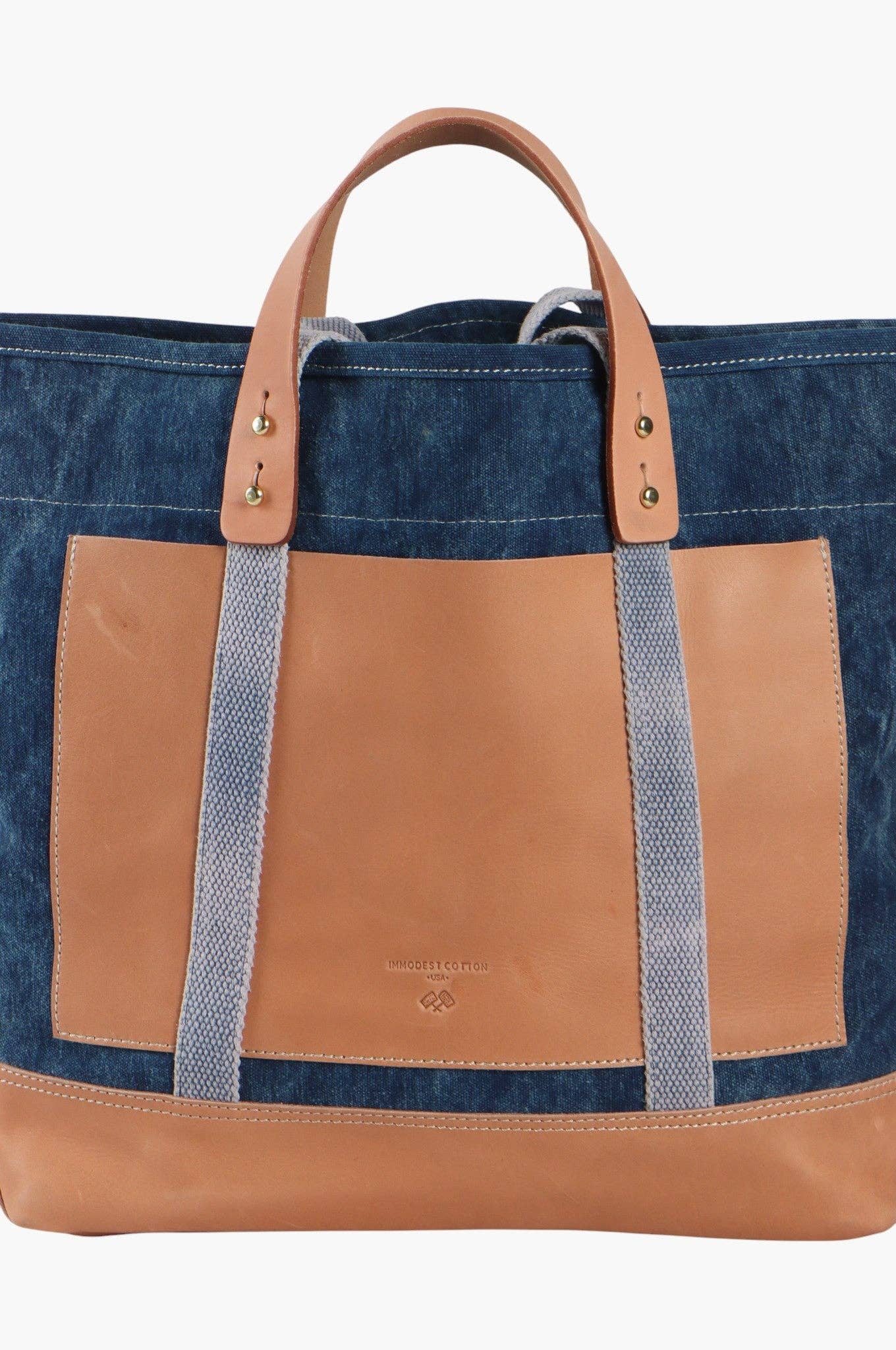 Editor Tote | Indigo + Tan with leather handles and denim body, featuring a spacious front pocket and brass hardware accents