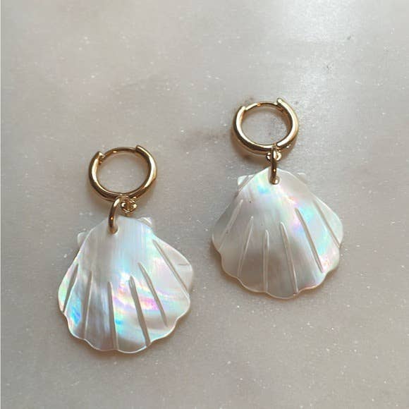 The Scallop Hoop Earrings by Tramps+Thieves feature gold-filled hoops with iridescent shell-shaped charms, shown on a light, textured surface.