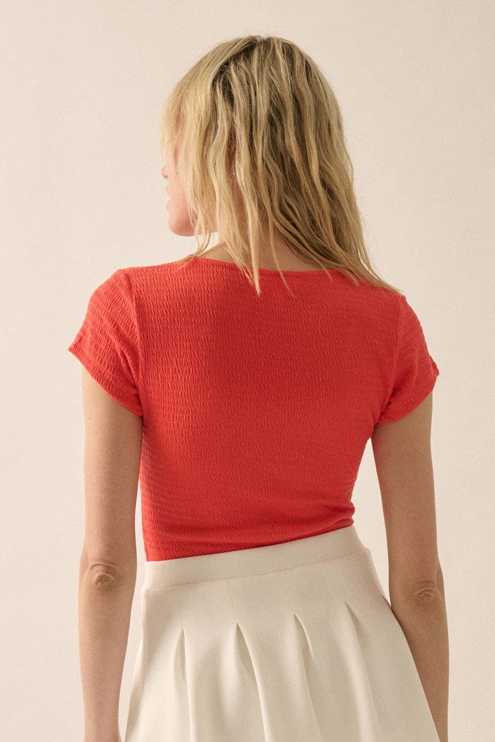 Woman wearing coral Smocked Jersey Scoop Neck Bodysuit showing textured fabric and short sleeves from the back