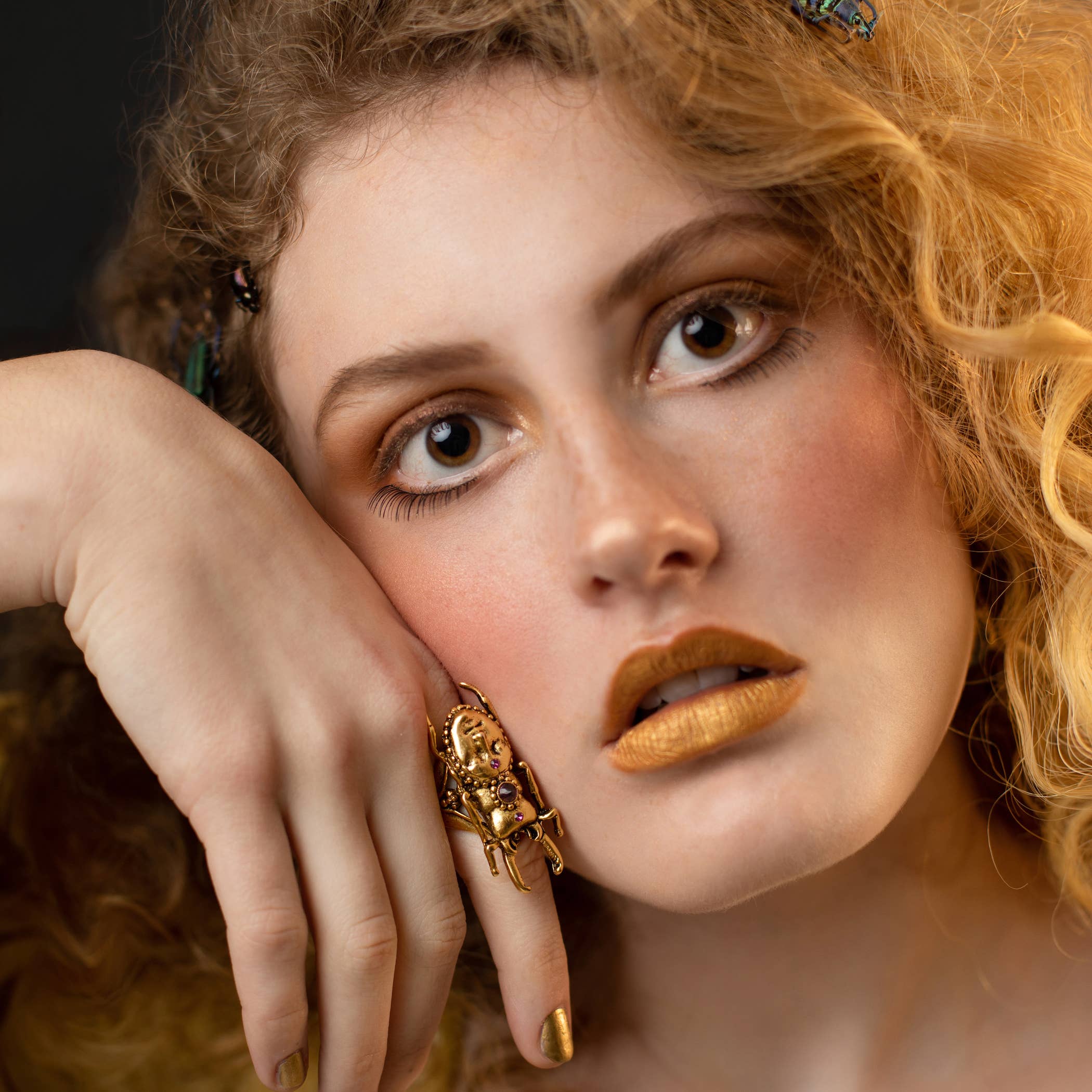Close-up of a woman wearing a bold gold Hidden Magic Stag Beetle Ring with artistic details on her finger