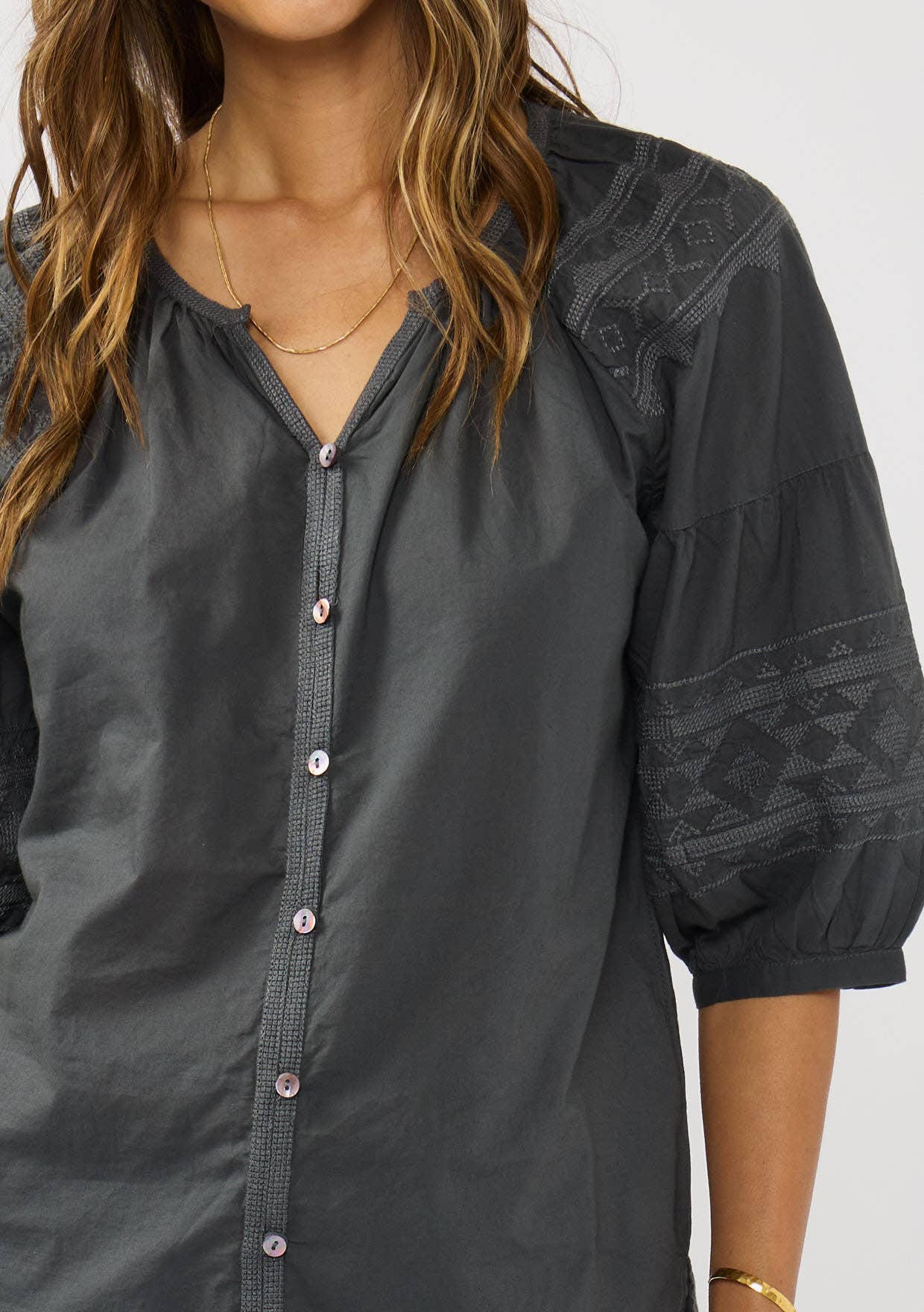 Woman wearing charcoal Short Raglan Puff Sleeve Button Down Top with textured sleeves and delicate buttons down front