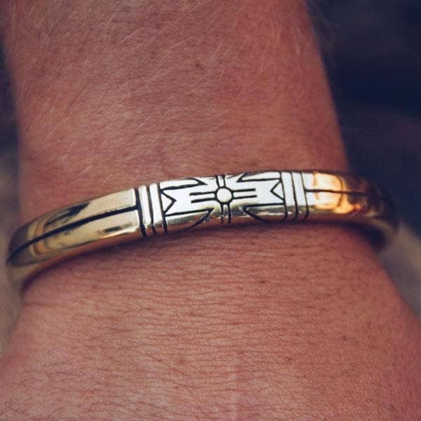 Close-up of a polished brass Medicine Wheel Cuff || Men featuring engraved Native-inspired design on wrist