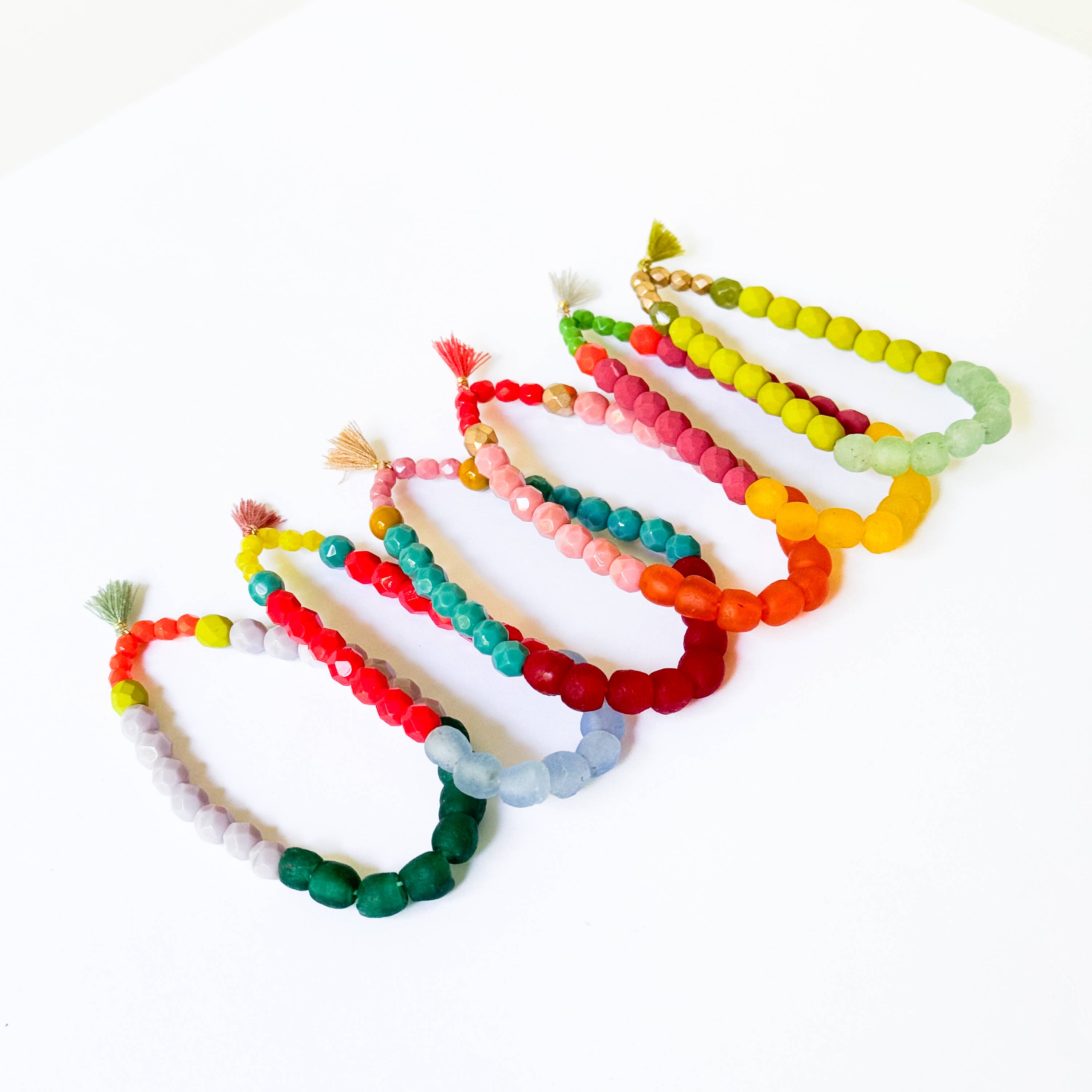 Multicolor Recycled African Glass And Mixed Bead Bracelet set featuring vibrant handcrafted beads and tassel accents in various colors.