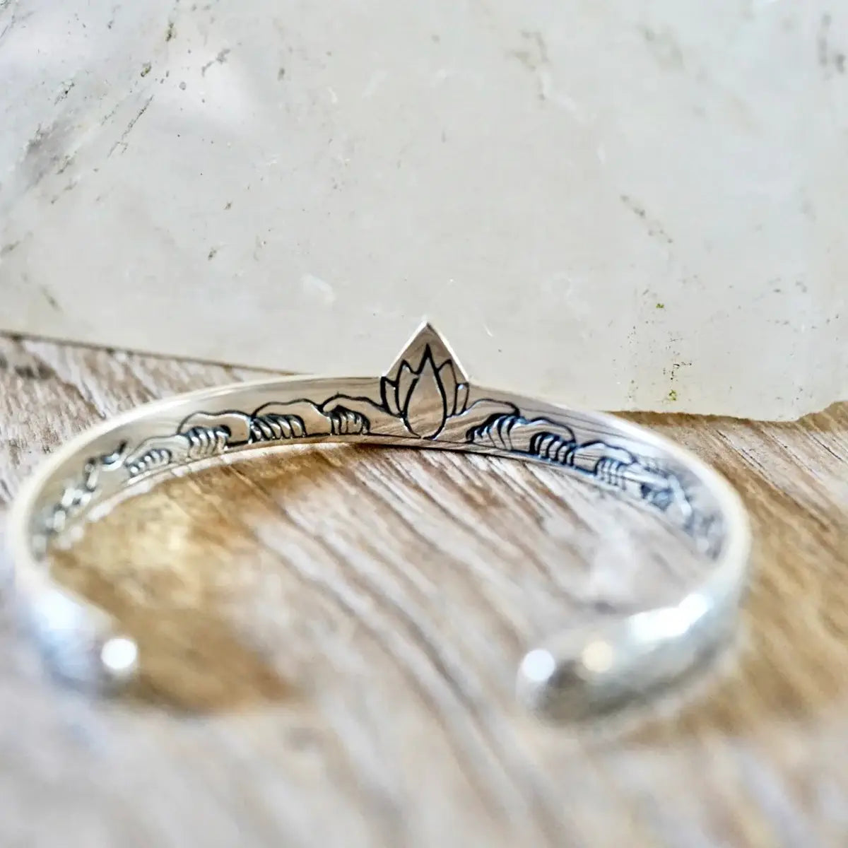 Delicate silver Hold Space Cuff with engraved lotus design, capturing a serene and artful statement piece style.