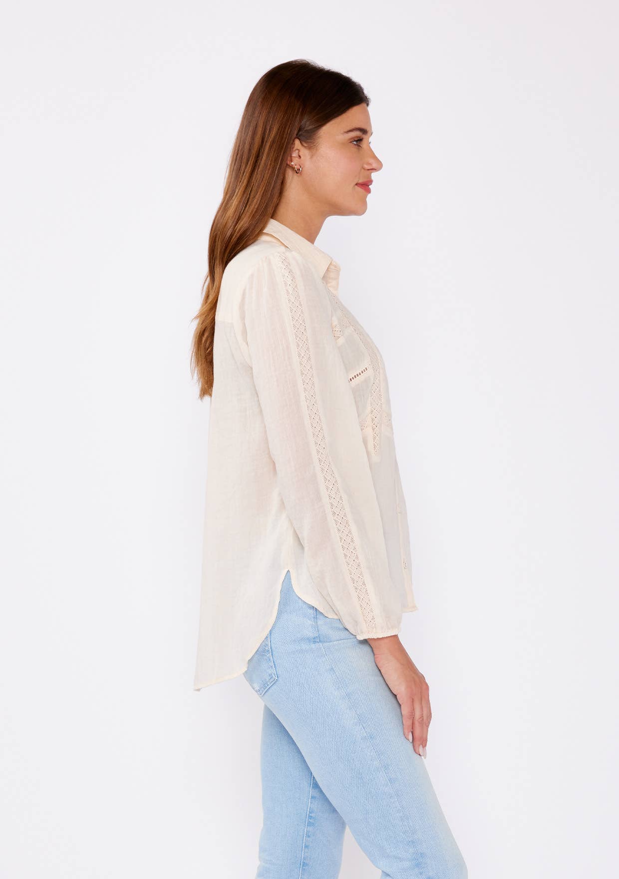 Woman wearing a cream Crinkled Lace Long Sleeve Button Down Blouse paired with light blue jeans against white background