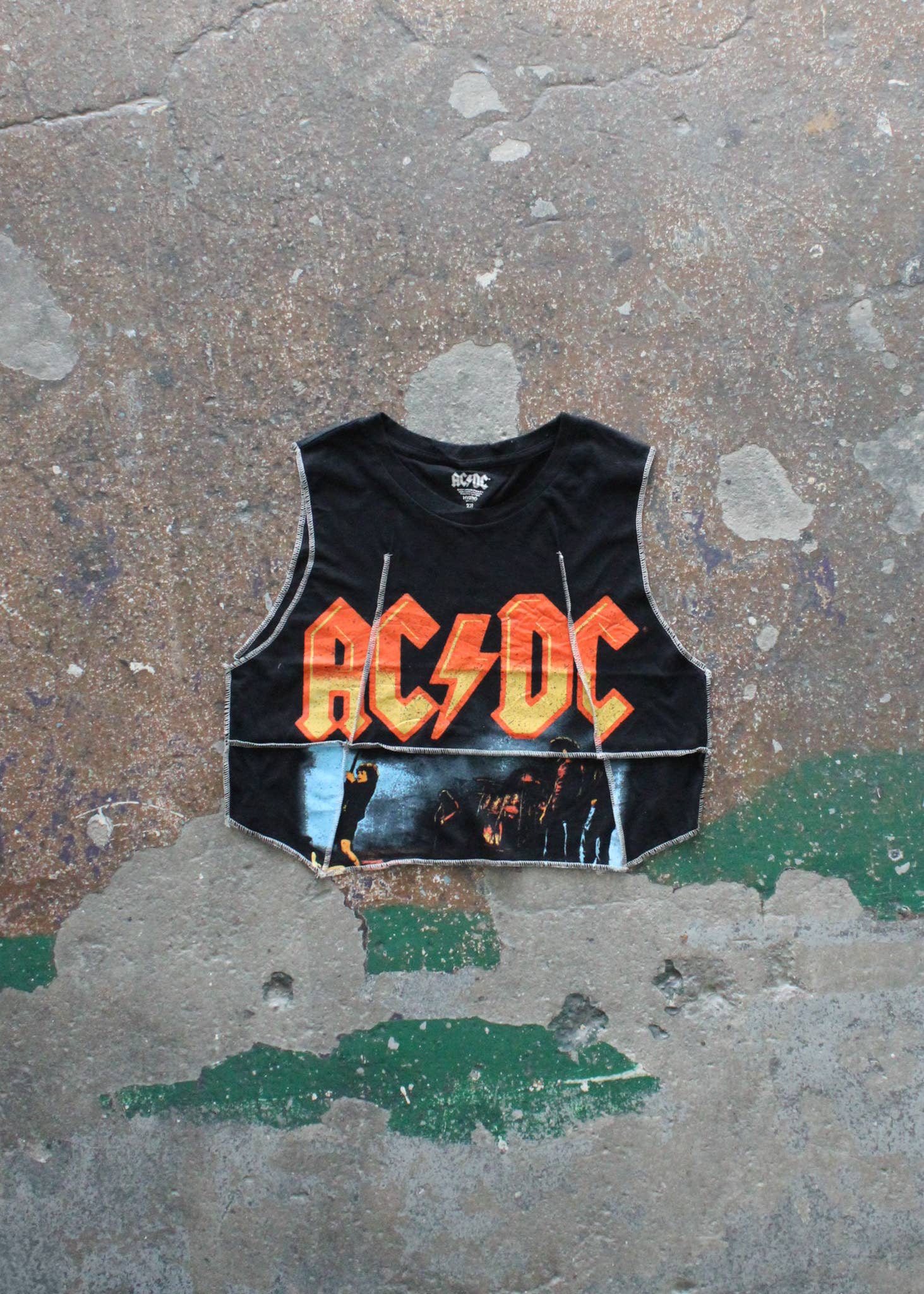 Overlock Cropped Music Muscle Tee in black with bold AC/DC graphic and raw edge details on a textured background