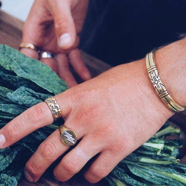 Close-up of a wrist wearing Medicine Wheel Cuff || Men with engraved tribal design on brass cuff bracelet.