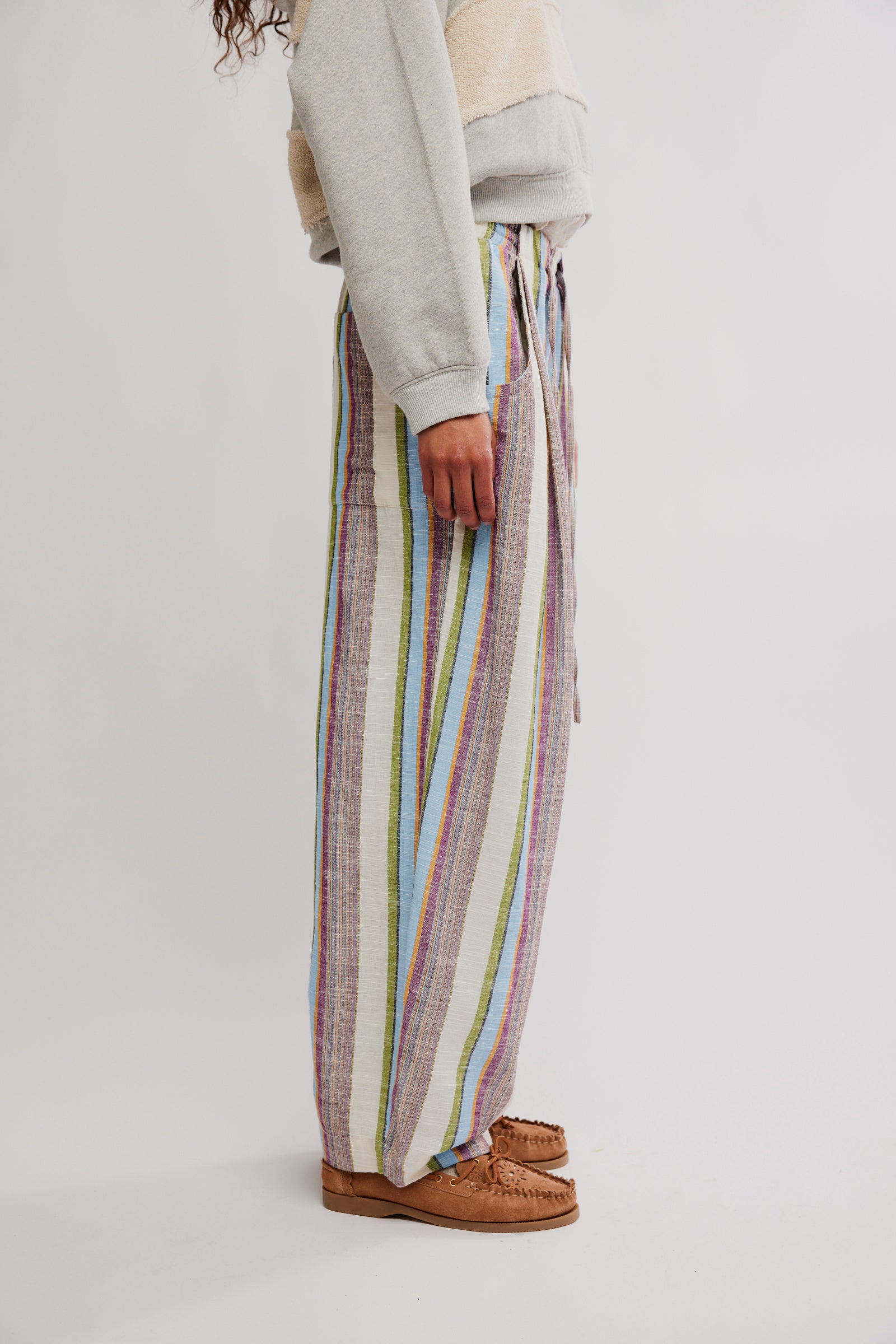 Side view of a person wearing Free People Chambers Laid Back Stripe Pull-On Pant in soft pastel vertical stripes with casual shoes