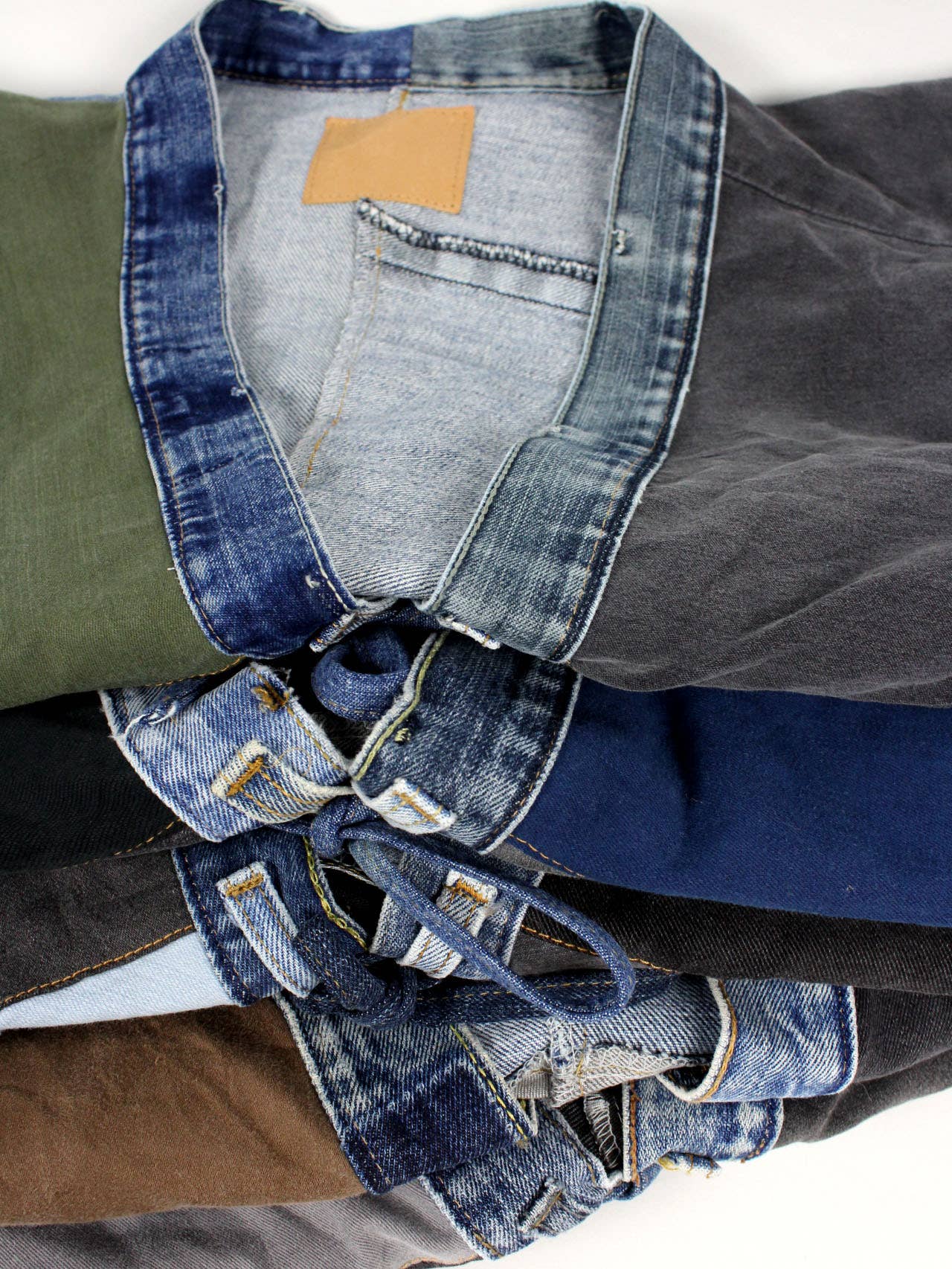 Close-up of folded Upcycled Patchwork Denim Jacket showing mixed denim and fabric panels with detailed stitching.
