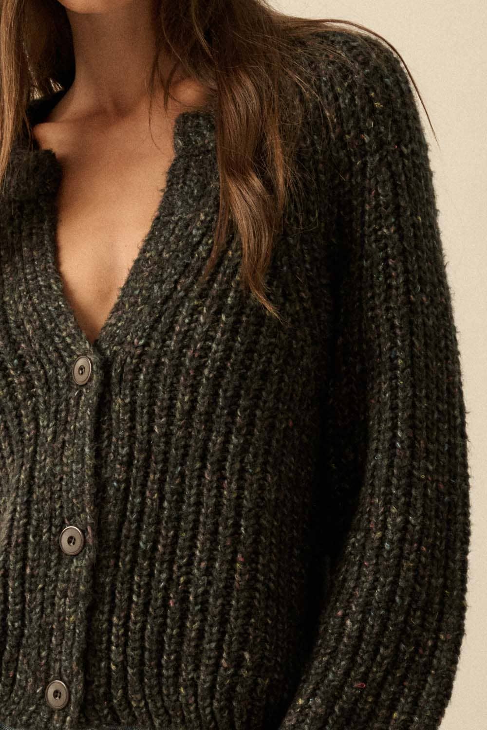 A close-up shows a person wearing the Promesa USA Confetti Button-Front Cardigan Sweater with a deep V-neck. Only part of their face and upper body are visible.
