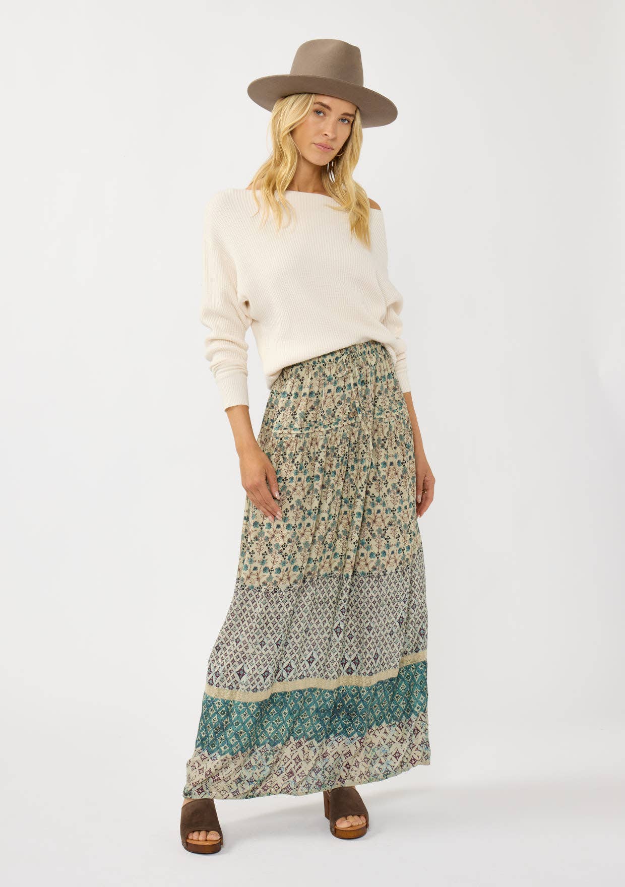 Woman wearing Floral and Tribal Border Drawstring Maxi Skirt with a cream sweater, brown sandals, and taupe hat.