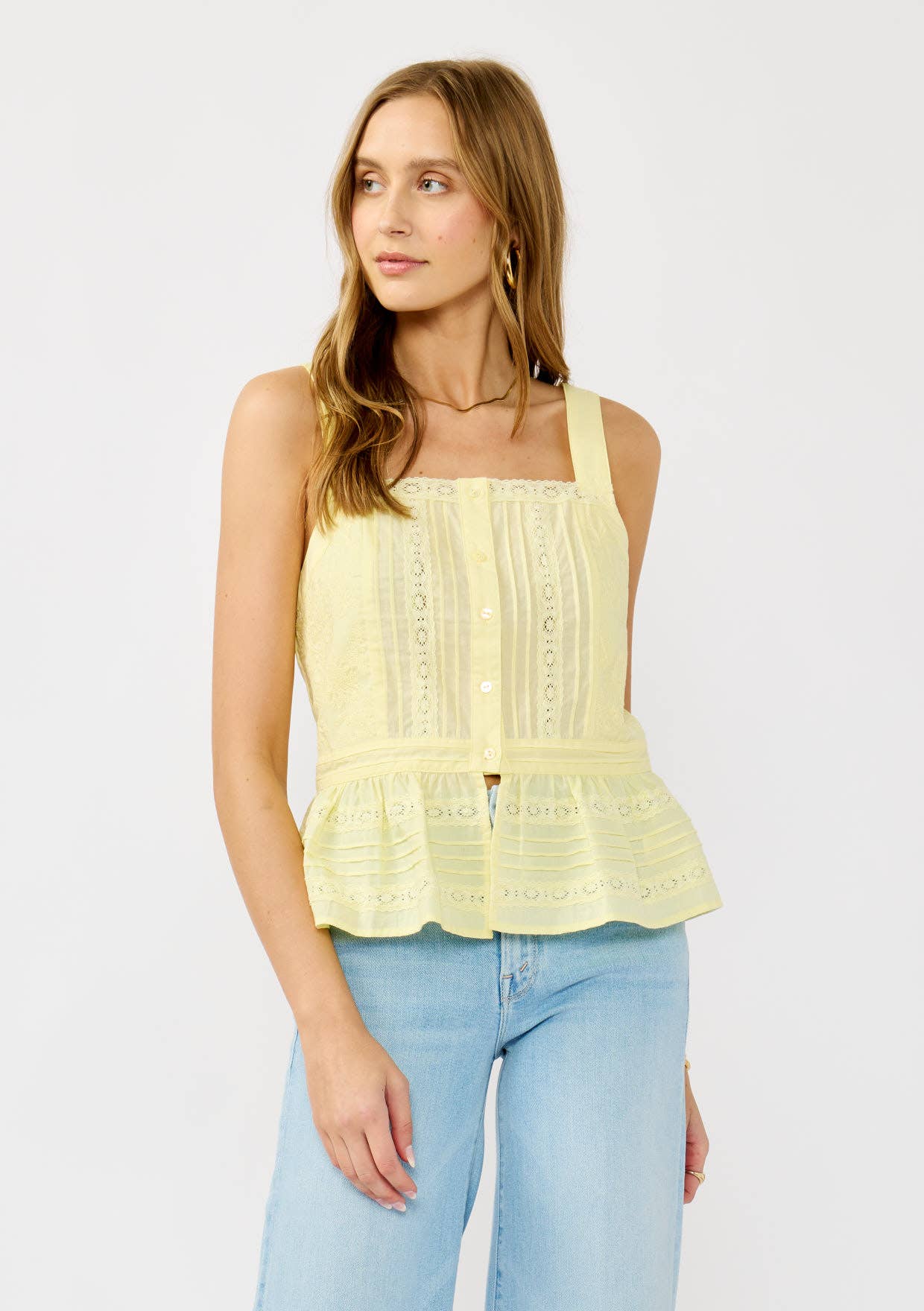 Woman wearing a light yellow Smocked Ruffle Lace Peplum Top with button front and lace detailing paired with jeans
