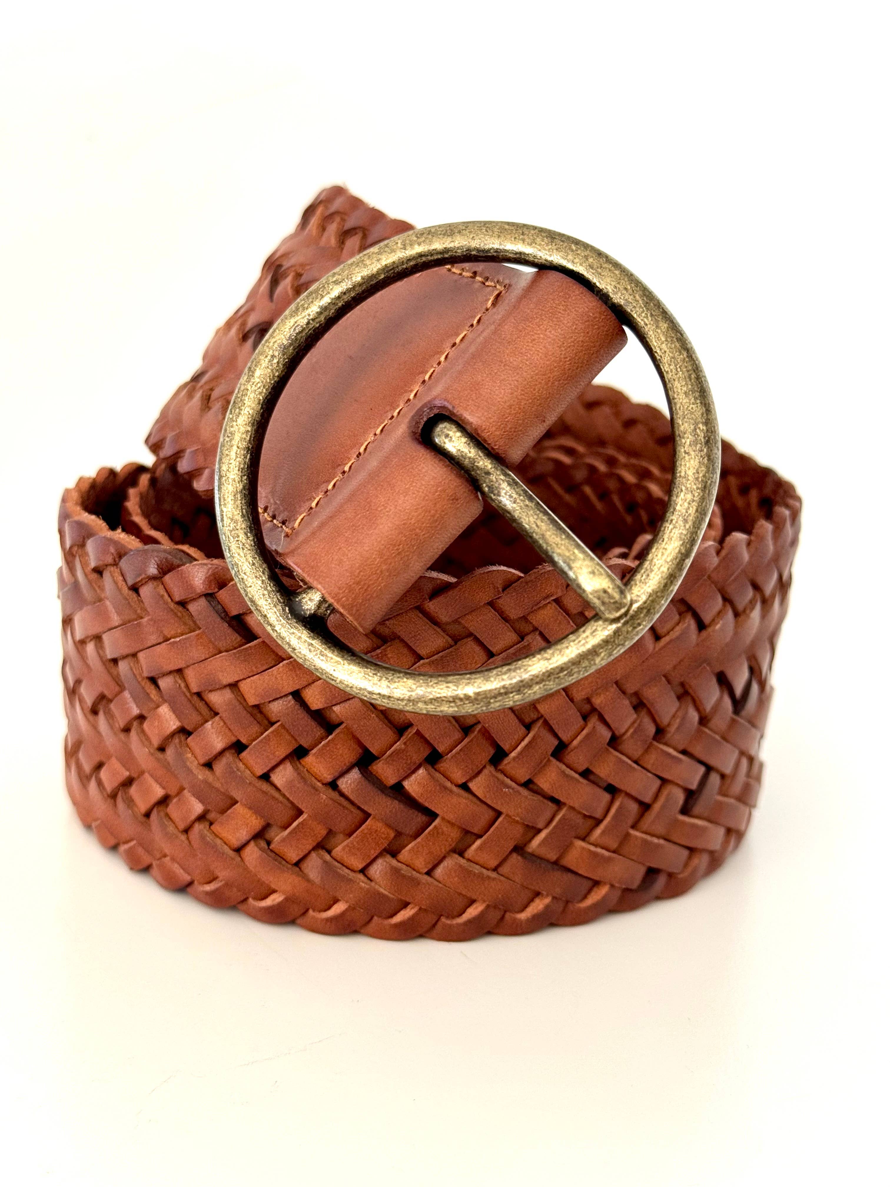 The Ginger Blue Classic Wide Braided Leather Belt in Cognac features woven genuine leather and a large round brass buckle, shown coiled on a white background.