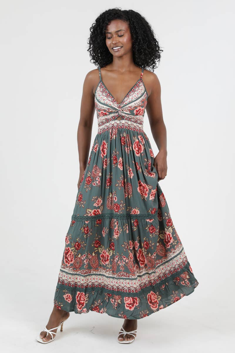 Woman wearing a floral patterned Golden Hour Twist Maxi Dress with thin straps and a flowing skirt smiling