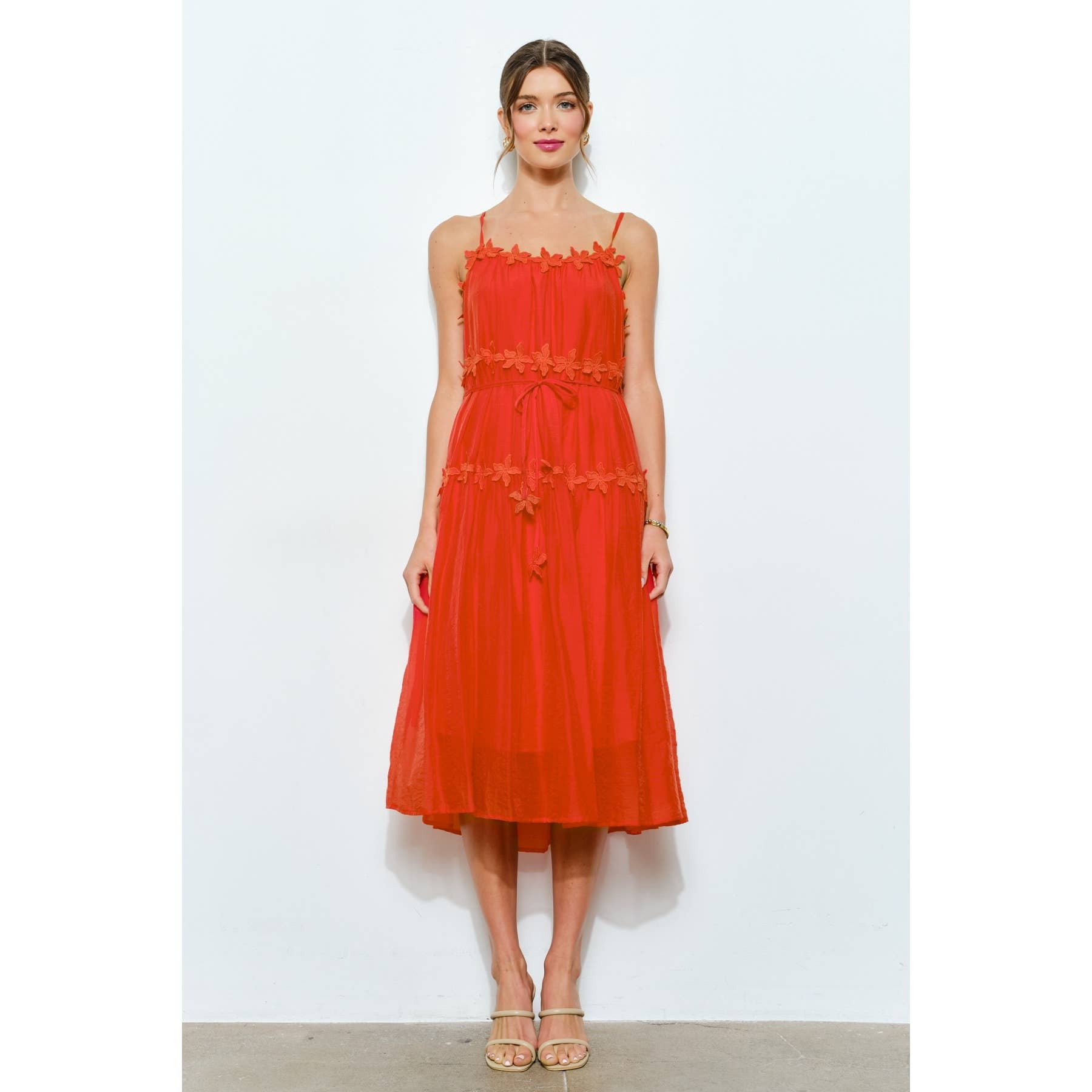 Woman wearing a red dress with floral details on a white background