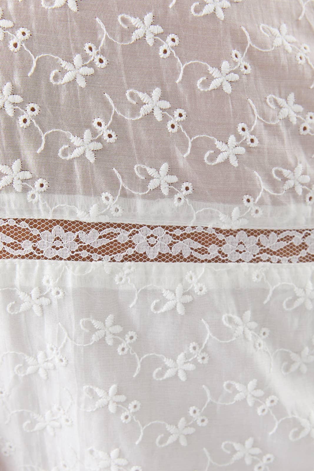 Close-up of delicate white embroidery and lace detail on the Eyelet Lace Mini Dress fabric design.