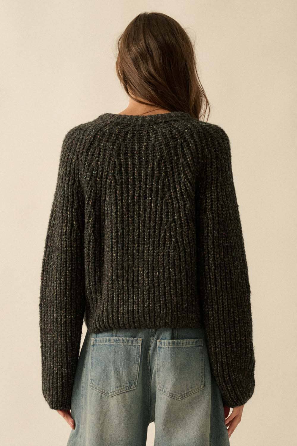 A person with long brown hair, seen from behind, wears the Promesa USA Confetti Button-Front Cardigan Sweater with light blue jeans against a plain beige background.