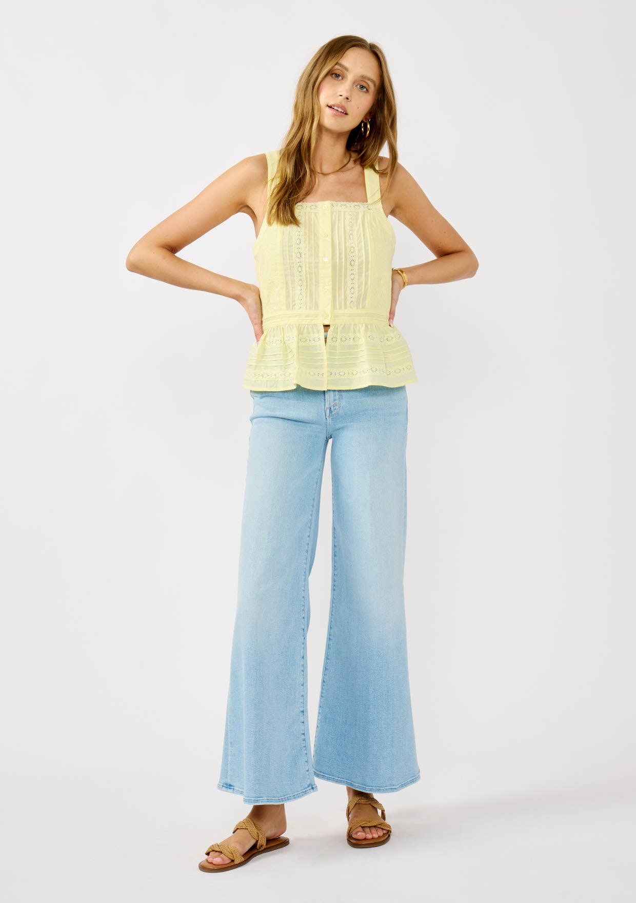 Woman wearing a light yellow Smocked Ruffle Lace Peplum Top paired with light blue wide-leg jeans and sandals.