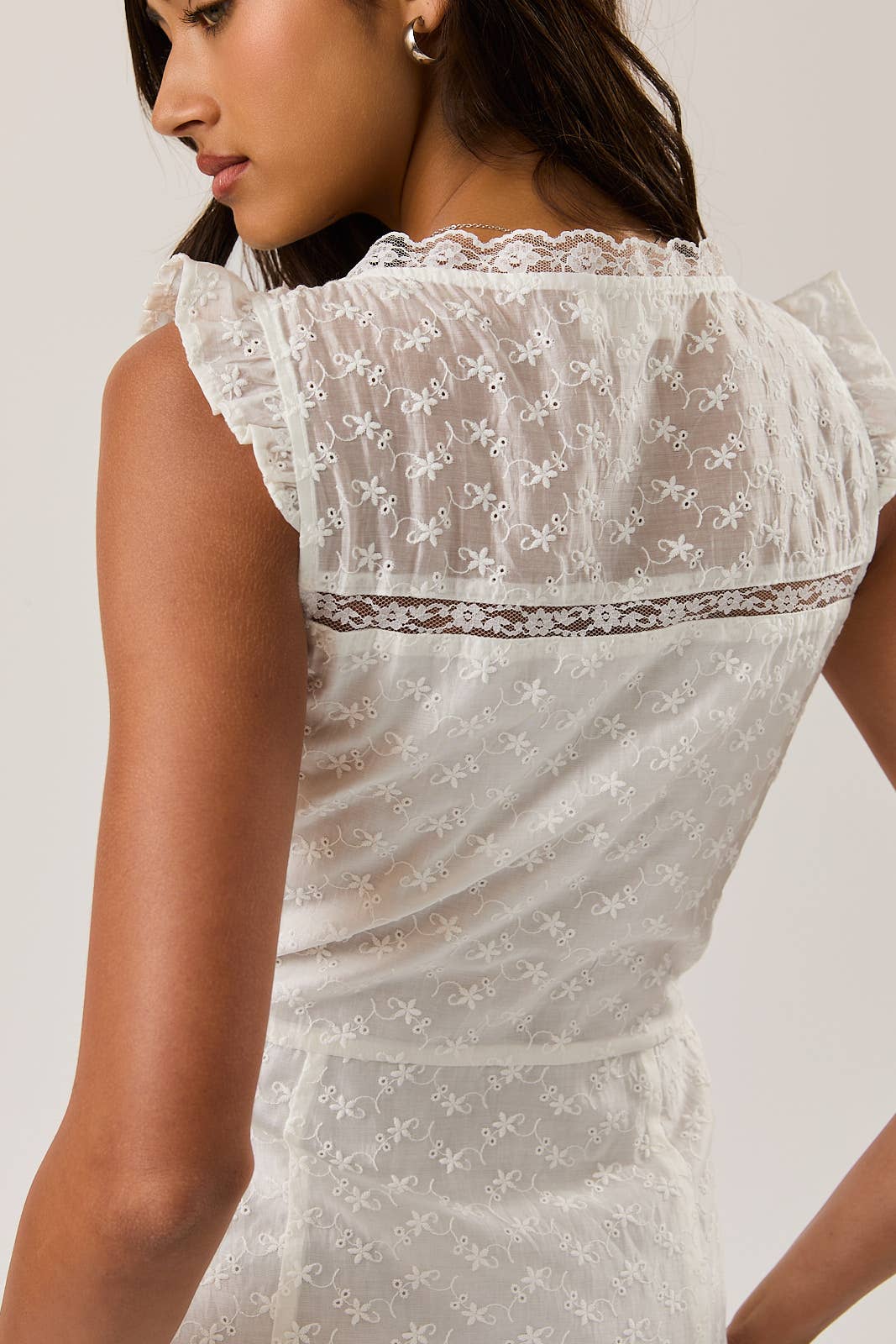 Close-up of delicate embroidered fabric details on the back of the Eyelet Lace Mini Dress worn by a model