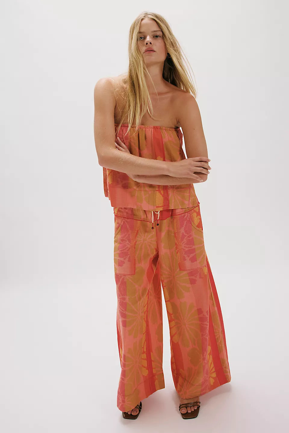 Woman wearing colorful strapless top and wide leg pants in floral print, styled in FREE PEOPLE DEVELLA SET