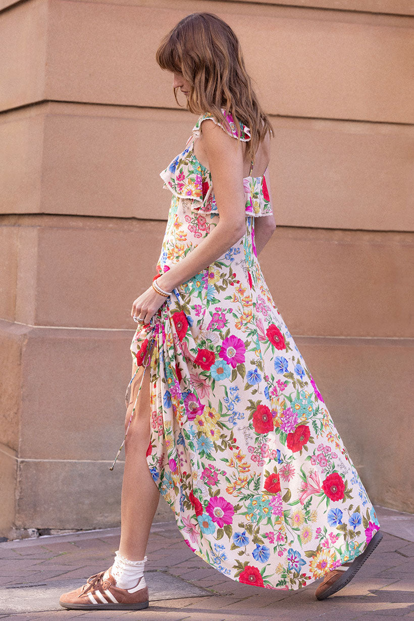 Woman walking outdoors wearing colorful floral Valley of the Dolls Strappy Gown with ruffle and side slit details