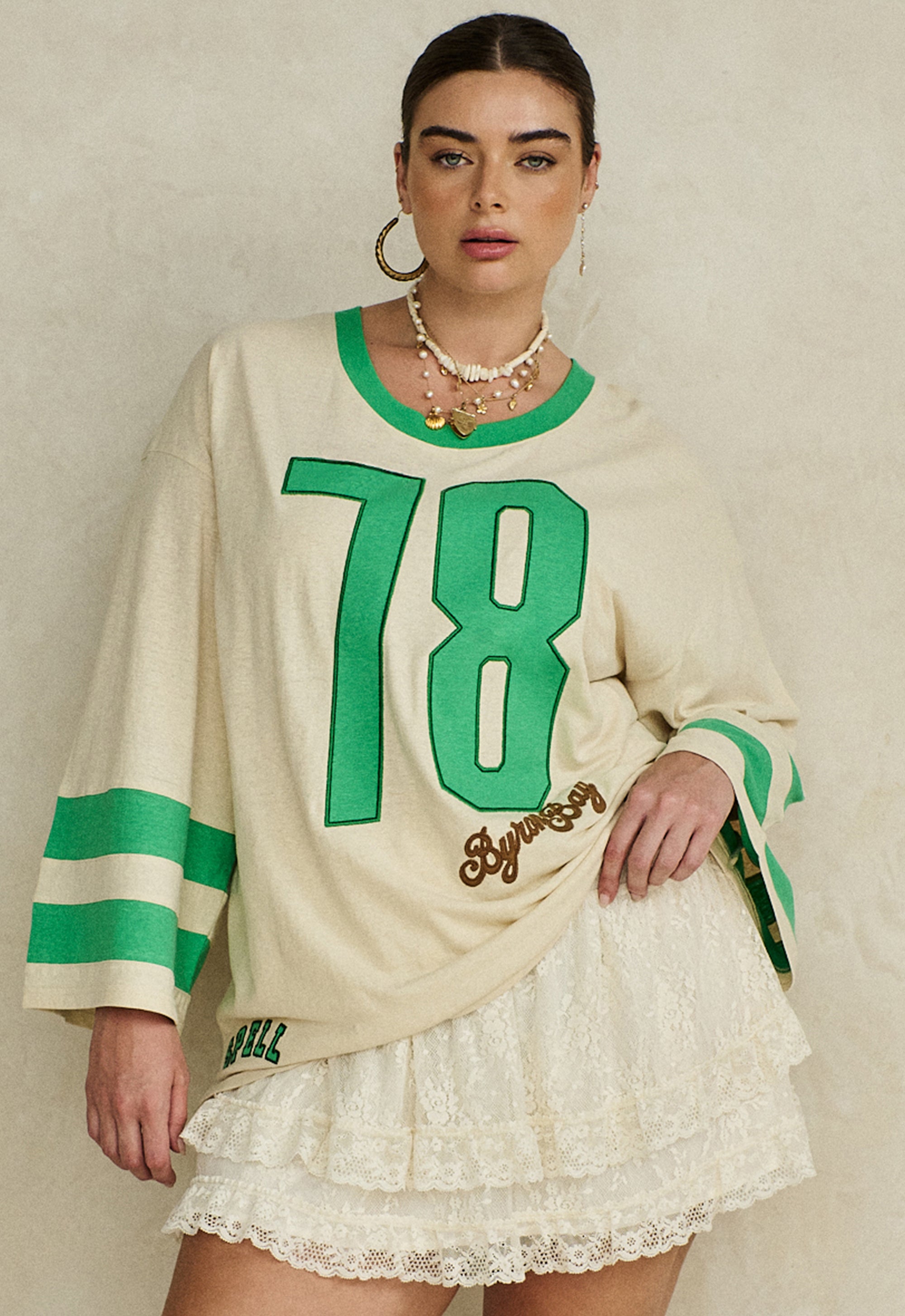 Woman wearing Homecoming Long Sleeve Biker Tee with green accents and large 78 graphic paired with lace skirt