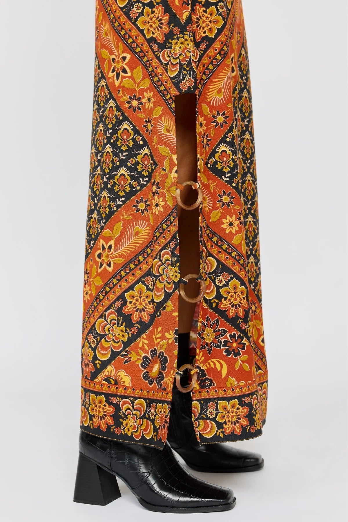 Close-up of the patterned hem and ring details of the Whitney Skirt in Saffron paired with black heeled boots