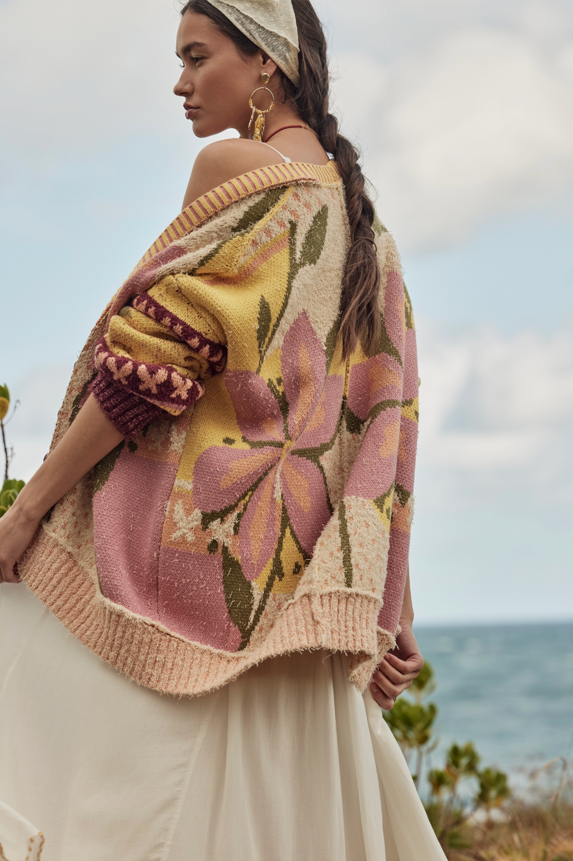 Woman wearing a colorful floral-patterned sweater with a blurred natural background