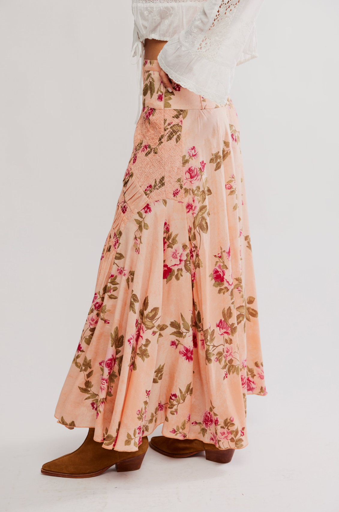 Wearing the Free People Rowan Maxi Skirt—a flowy, rose floral maxi—paired with a white lace-detailed blouse and brown pointed-toe boots.