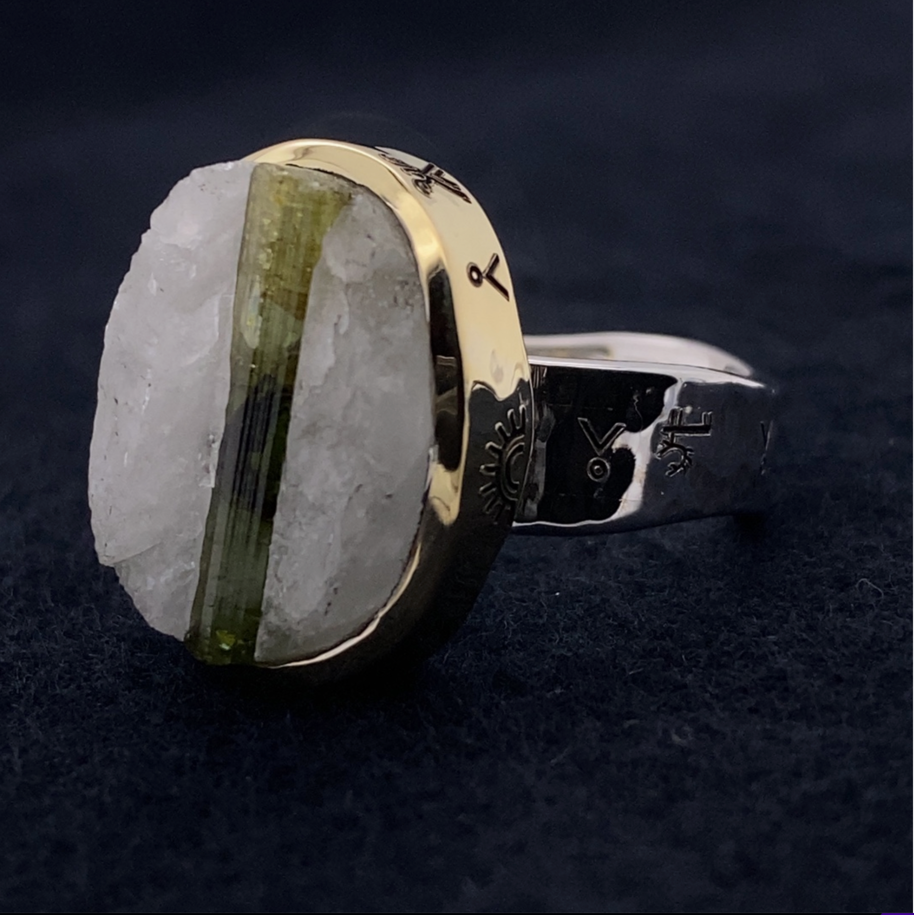Ring with a large stone and gold band on a dark background