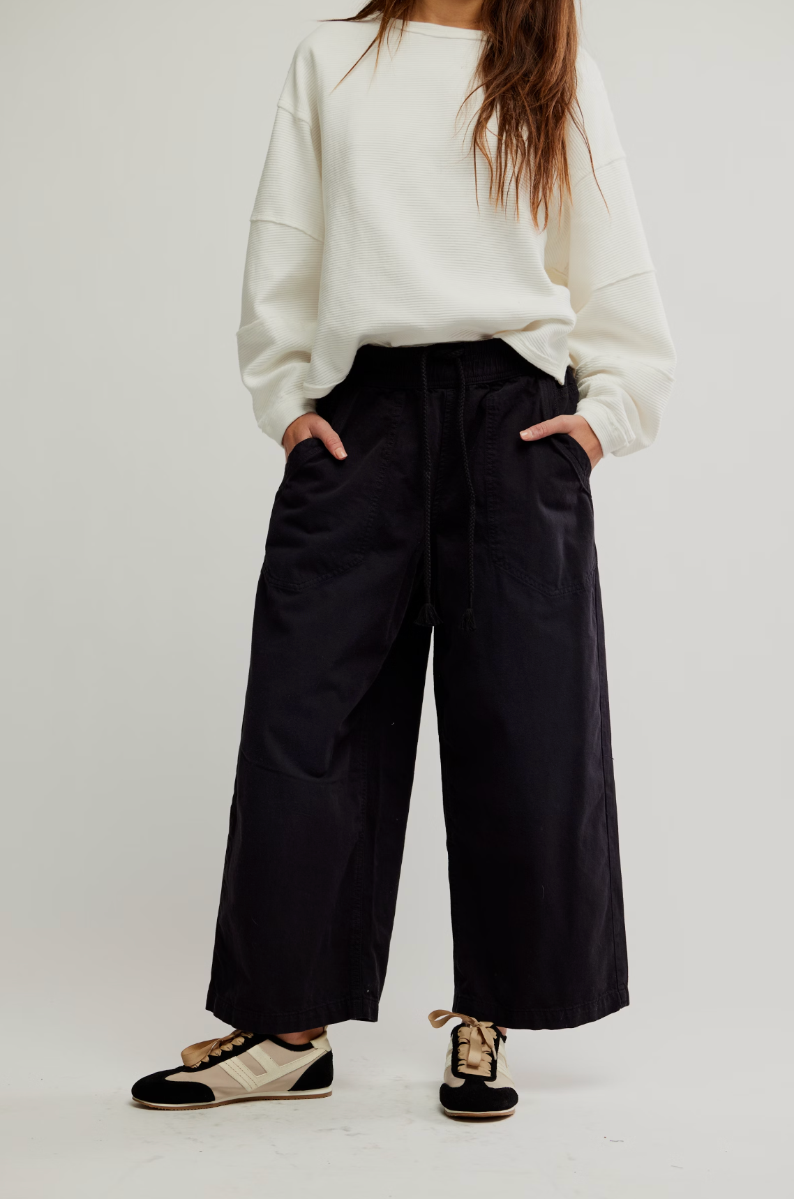 Woman wearing loose black pants and white sweatshirt styled with We The Free Easy Peasy Pull-On Jeans in a relaxed pose