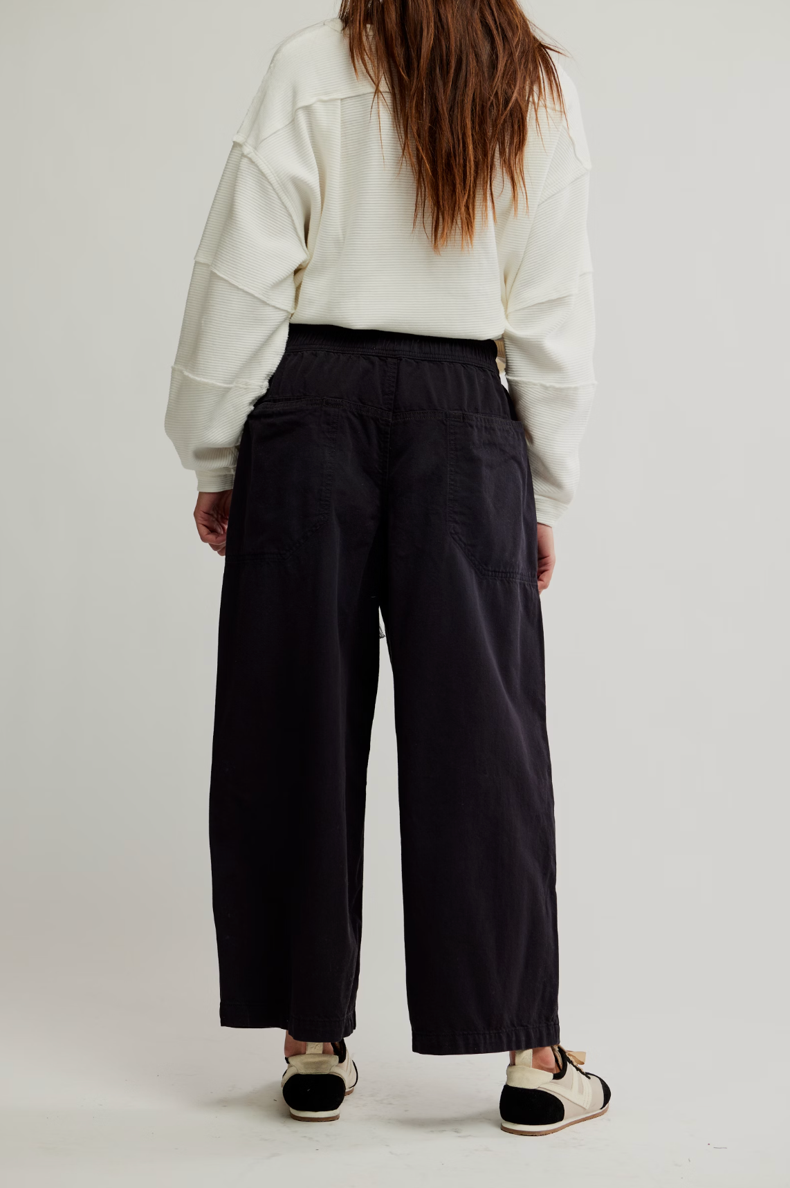 Woman wearing black We The Free Easy Peasy Pull-On Jeans with wide legs and elastic waistband, styled with a white top and casual shoes