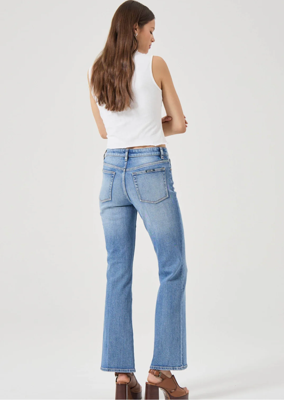Woman wearing Rolla's Midtown Boot in Blue Iris styled with white sleeveless top and brown platform sandals back view