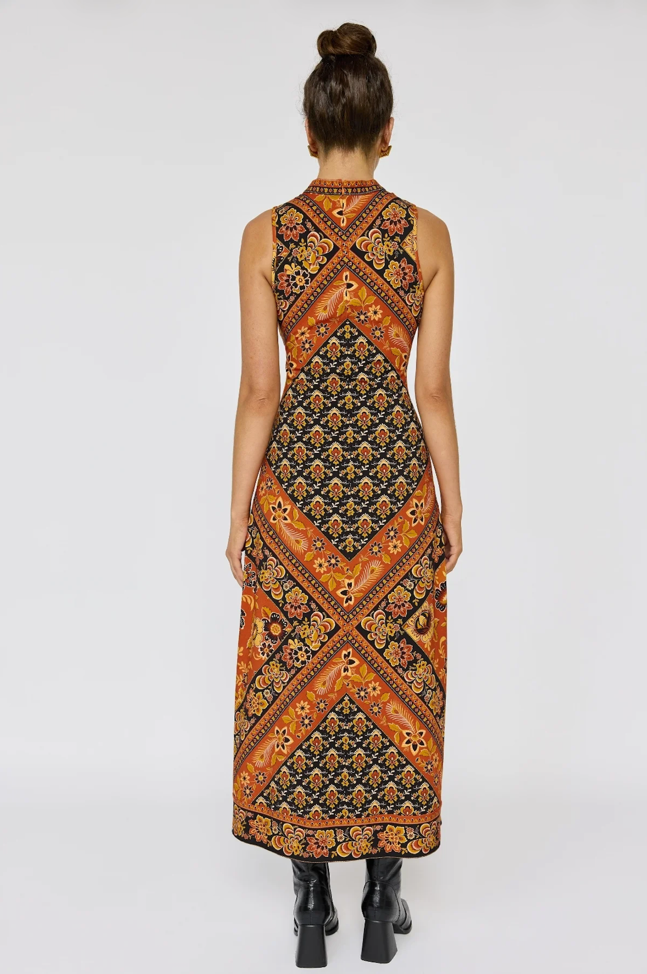 Woman wearing Sydney Midi Dress in Saffron with intricate floral and geometric patterns, styled with black ankle boots.