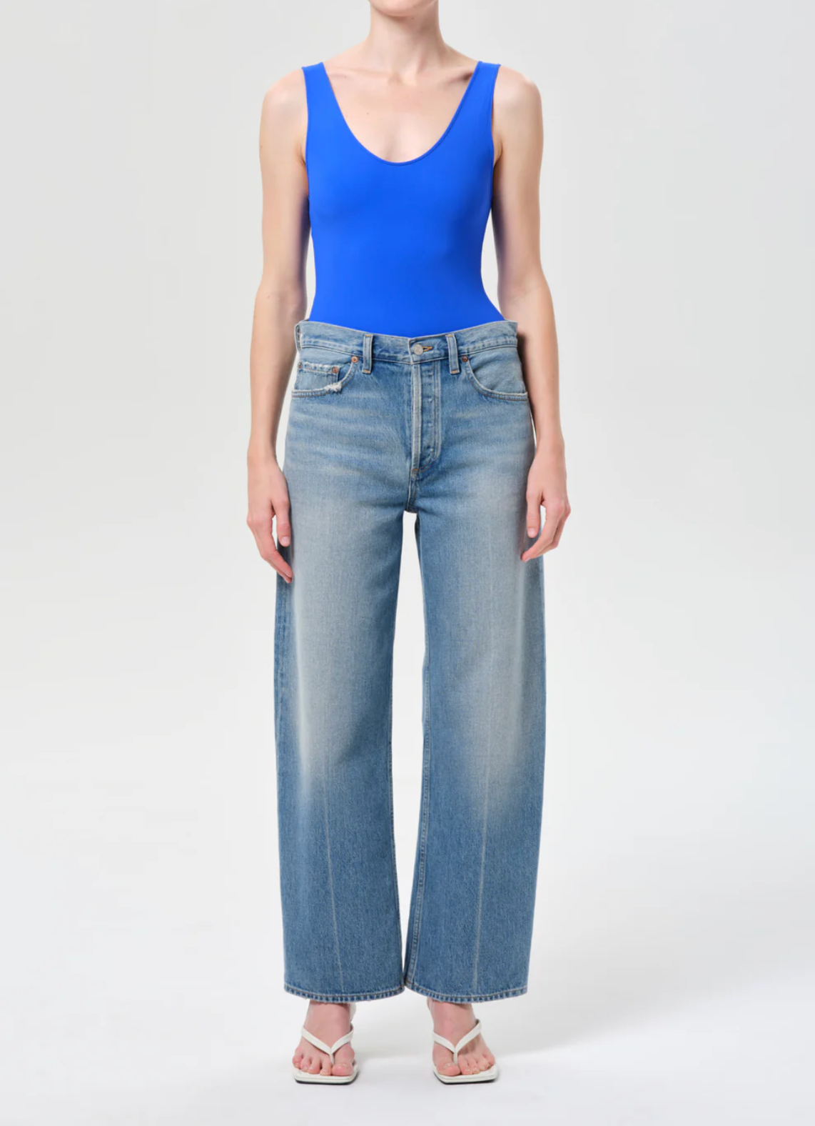 Front view of model wearing light wash wide-leg denim styled with blue top and sandals in Arc Jean 29" In Brink by Agolde