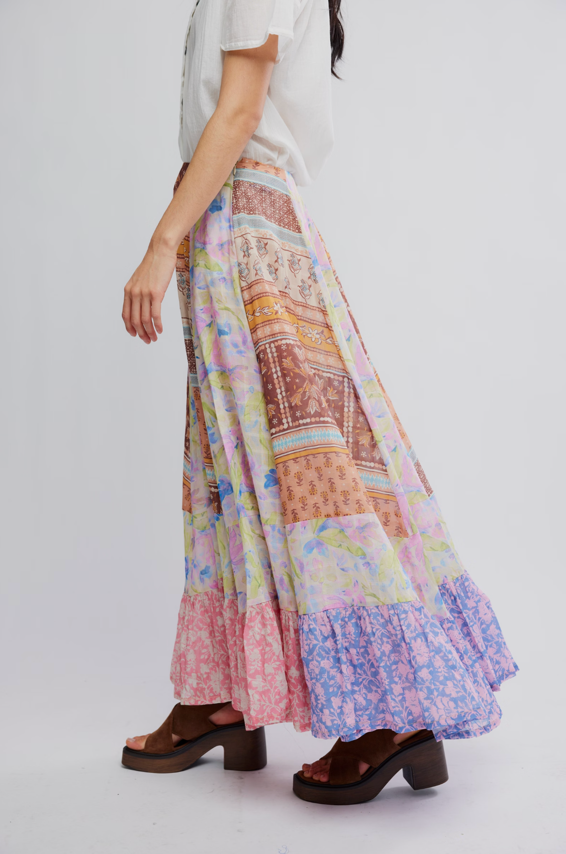 Side view of flowing colorful Santa Eulalia Printed Maxi Skirt by Free People worn with white blouse and platform sandals
