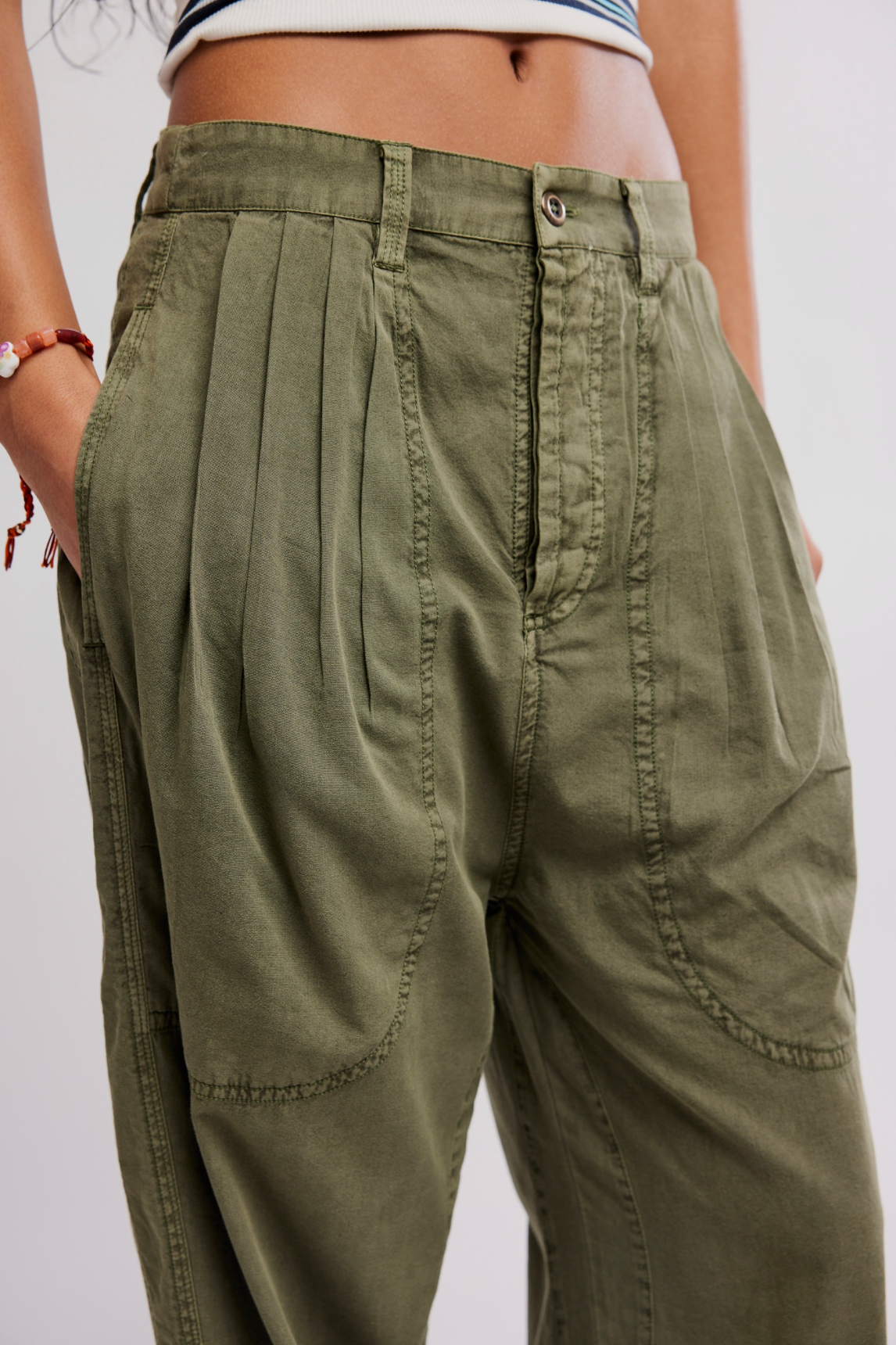 Close-up of olive green Clover Dropped Trouser by Free People with pleated front and relaxed fit.