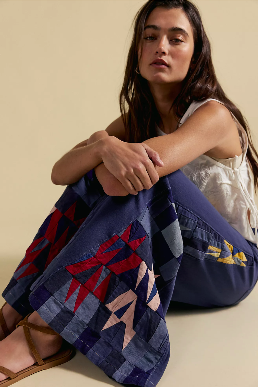 Woman sitting wearing Wild Rebel Jean by Free People – We The Free with colorful geometric patchwork on blue denim