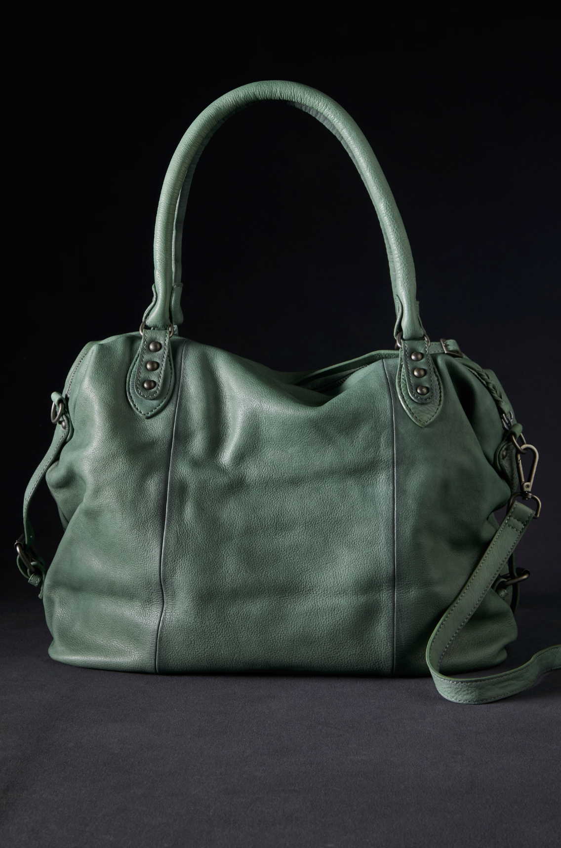 We The Free Emerson Tote Bag in Secret Sage with textured soft leather and brass details against dark background
