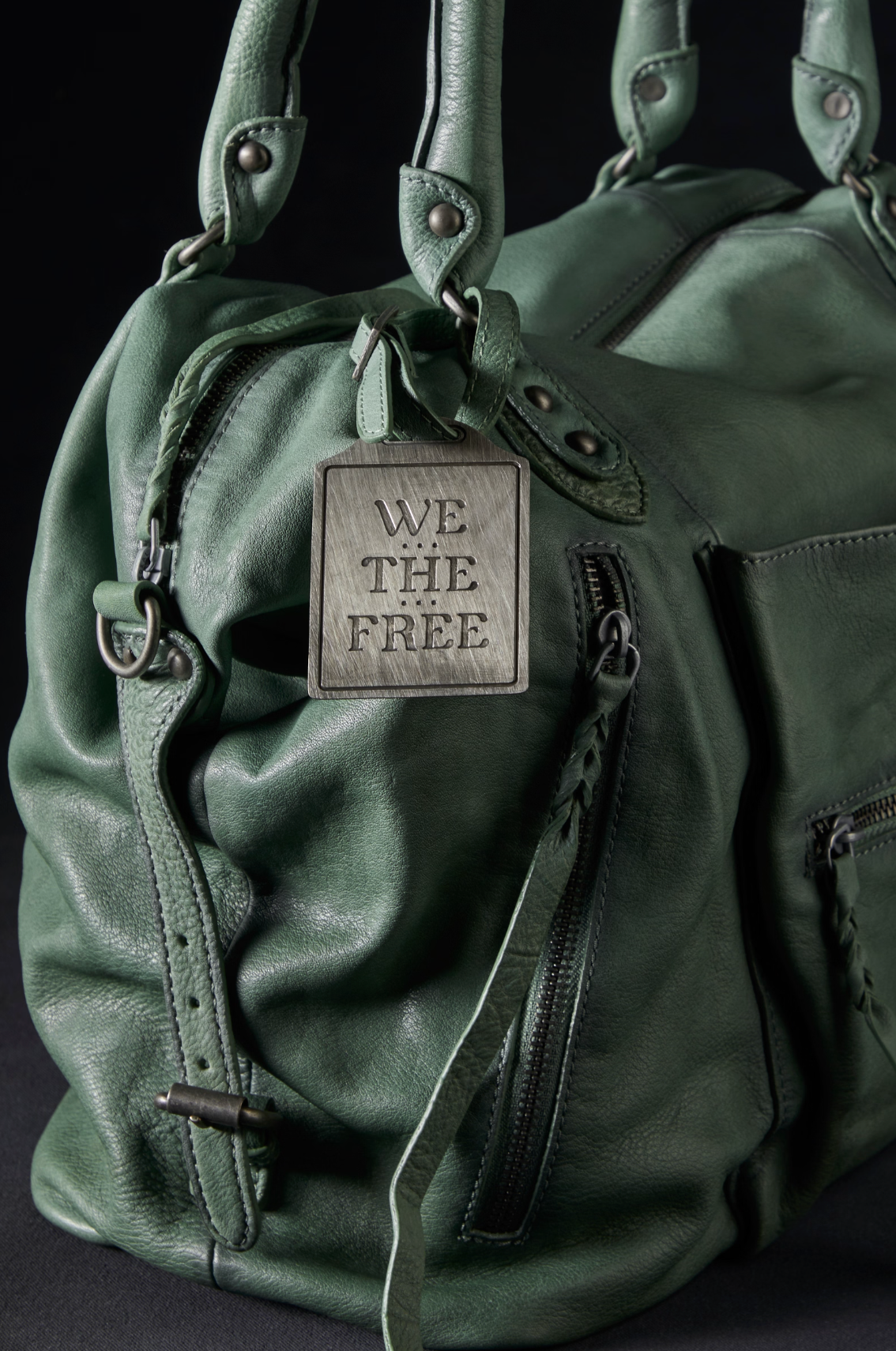 Close-up of We The Free Emerson Tote Bag in Secret Sage showing soft textured leather and metal tag detail on handles.