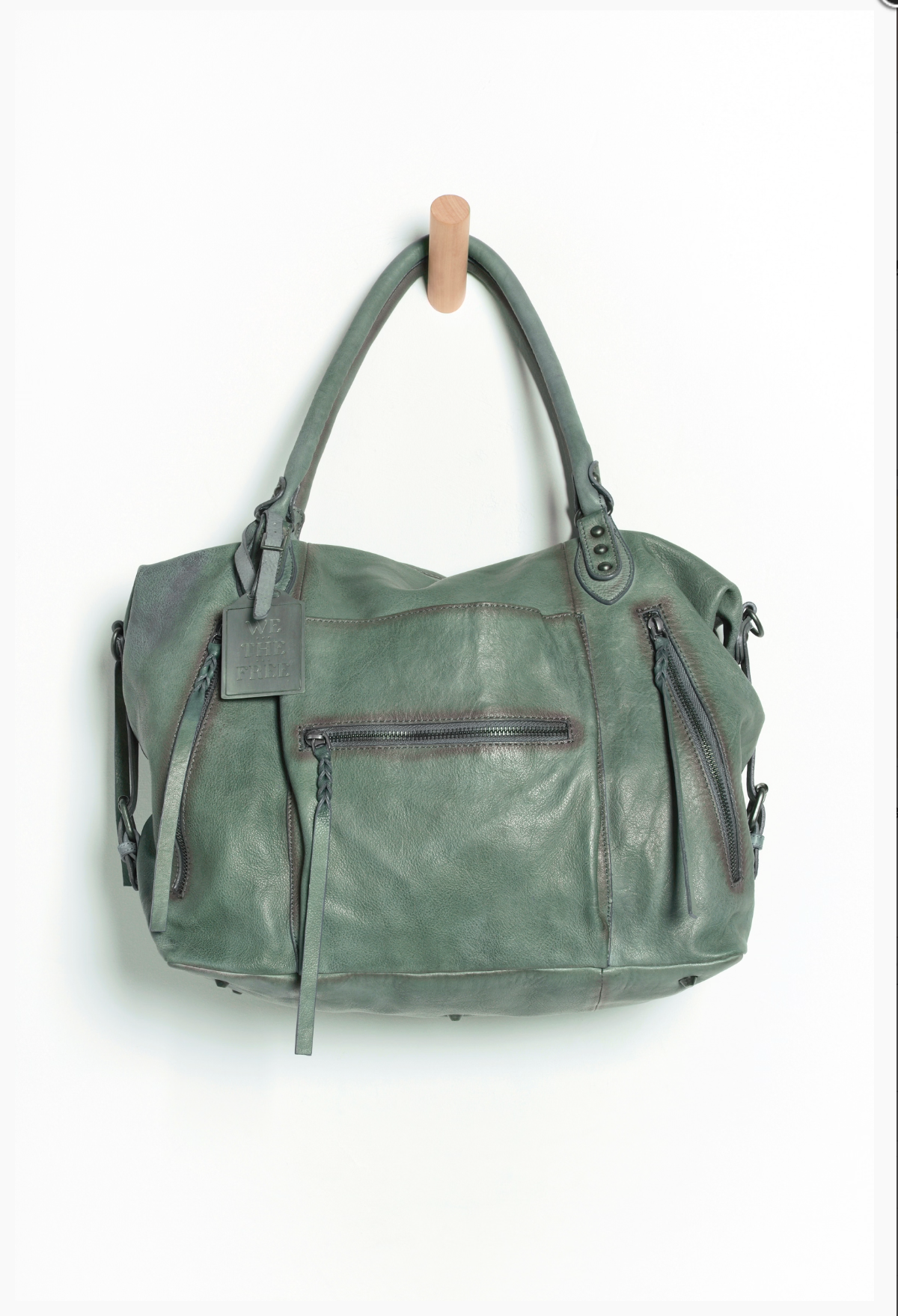 We The Free Emerson Tote Bag in Secret Sage hanging on wooden hook, soft leather texture, roomy design