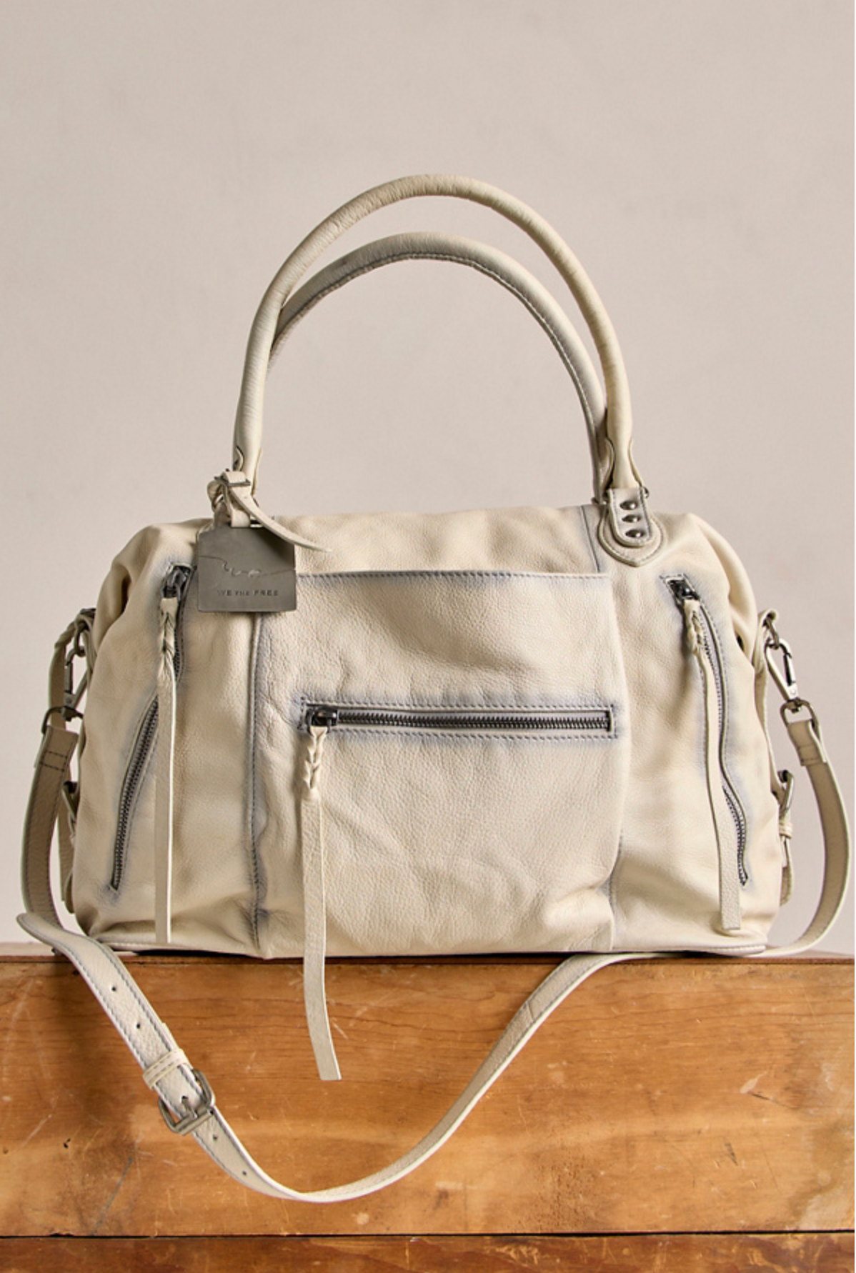 We The Free Emerson Tote Bag in Salt, soft textured fabric with multiple zip pockets and dual handles on wooden surface.