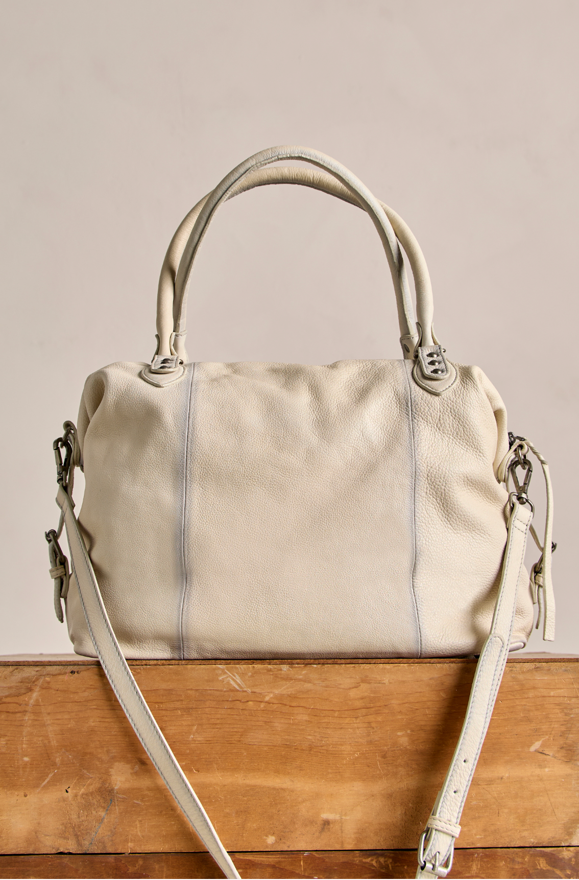 We The Free Emerson Tote Bag in Salt with soft leather texture and dual handles resting on a wooden surface