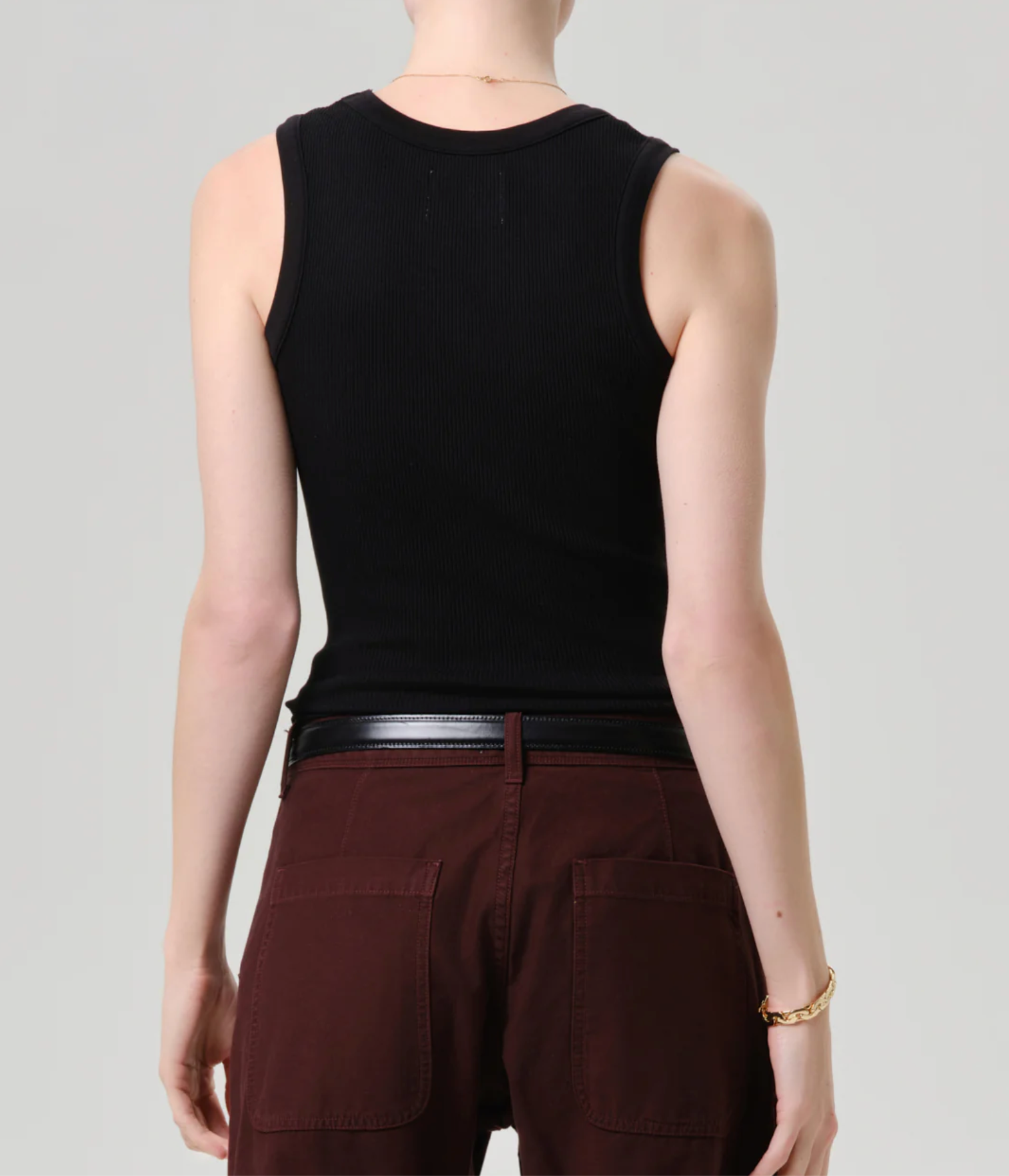 Model wearing The Nova Tank by Citizens of Humanity in Black, paired with brown pants and gold bracelet, back view.