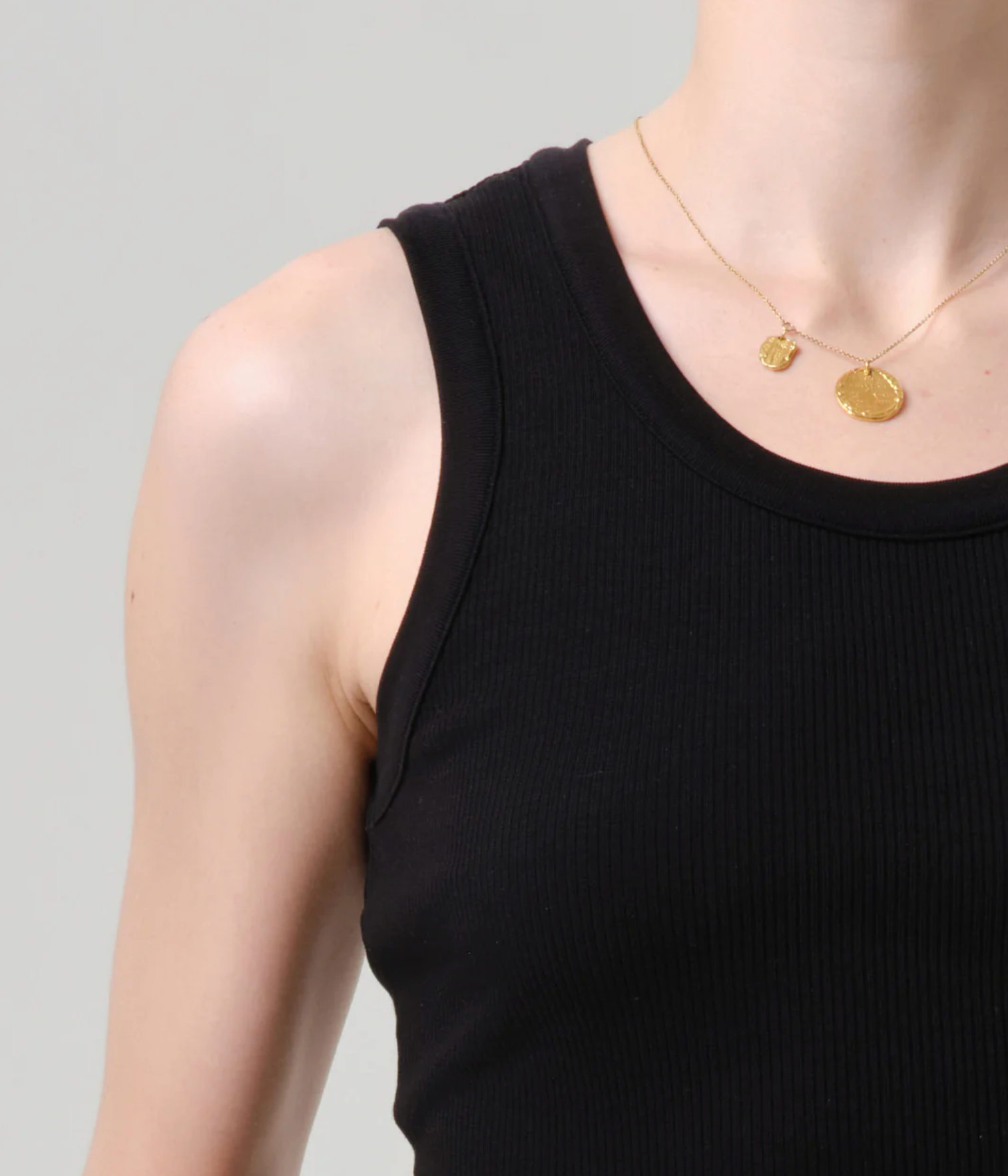 Close-up of a person wearing The Nova Tank by Citizens of Humanity in Black with a delicate gold pendant necklace