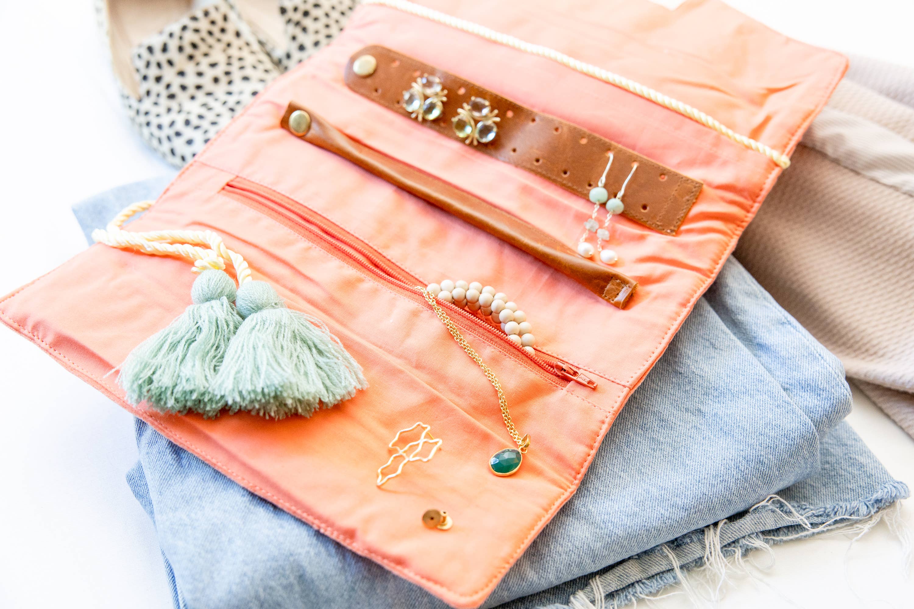Embroidered Velvet Jewelry Organizer-Coral open with earrings, bracelets, necklaces, and tassels on light fabric background